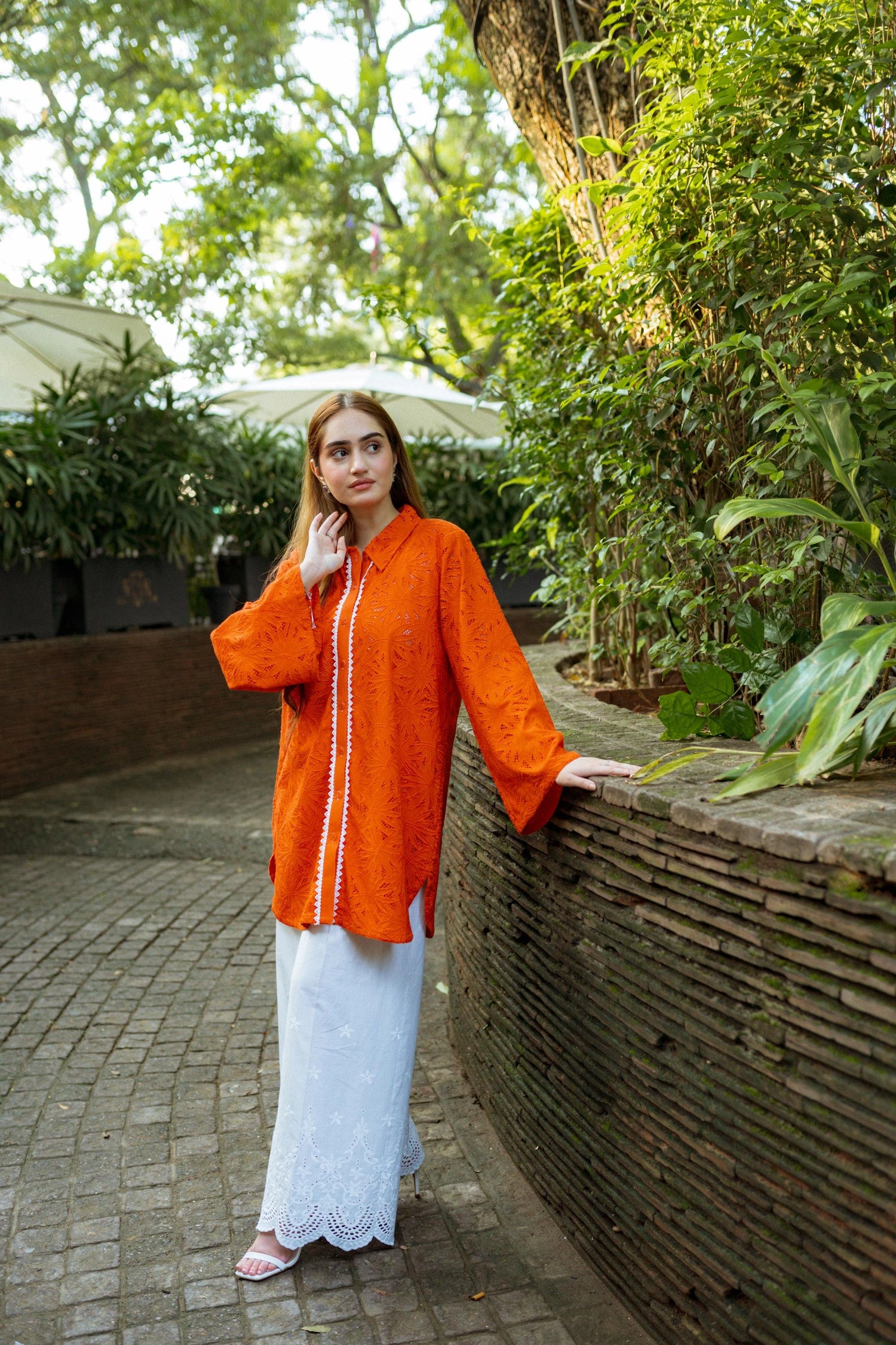 Stylish blunt orange short button-down shirt with a refined collar, contemporary round hem, and intricate lace along the buttons.
