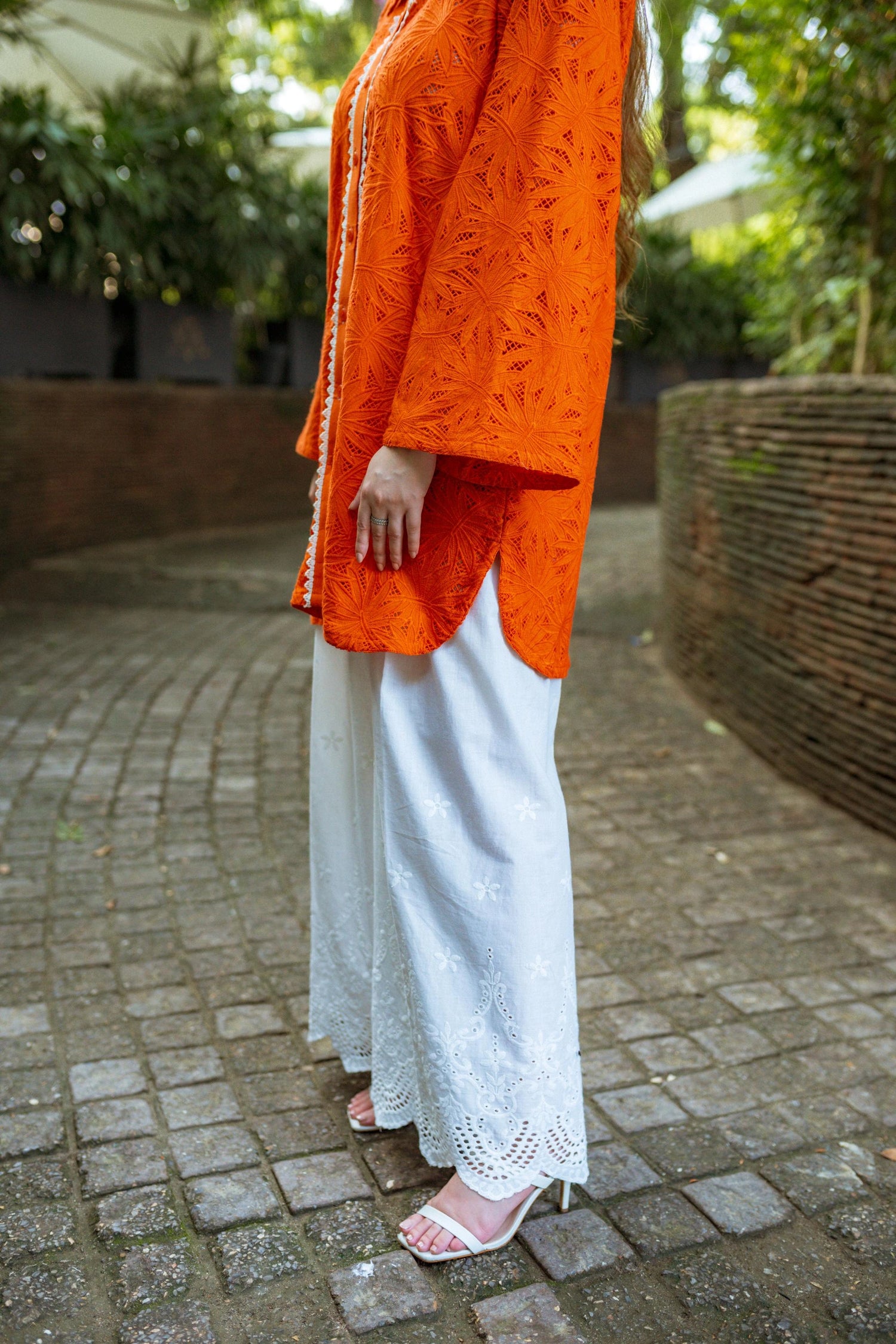 Stylish blunt orange short button-down shirt with a refined collar, contemporary round hem, and intricate lace along the buttons.
