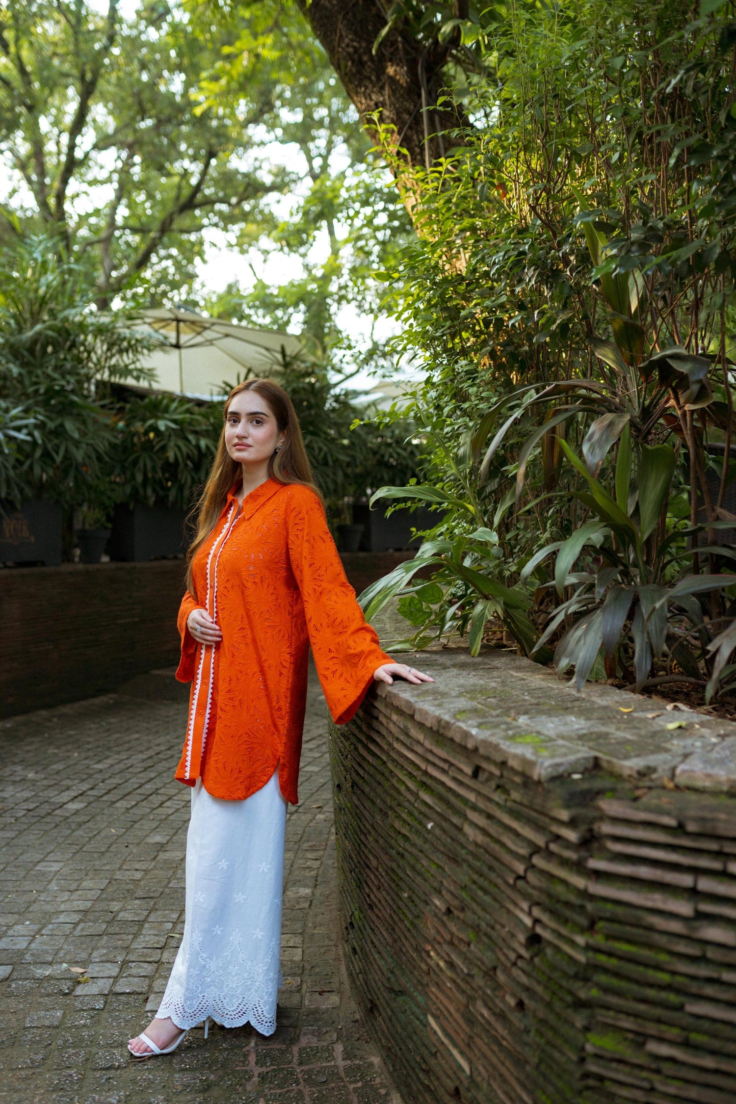 Stylish blunt orange short button-down shirt with a refined collar, contemporary round hem, and intricate lace along the buttons.