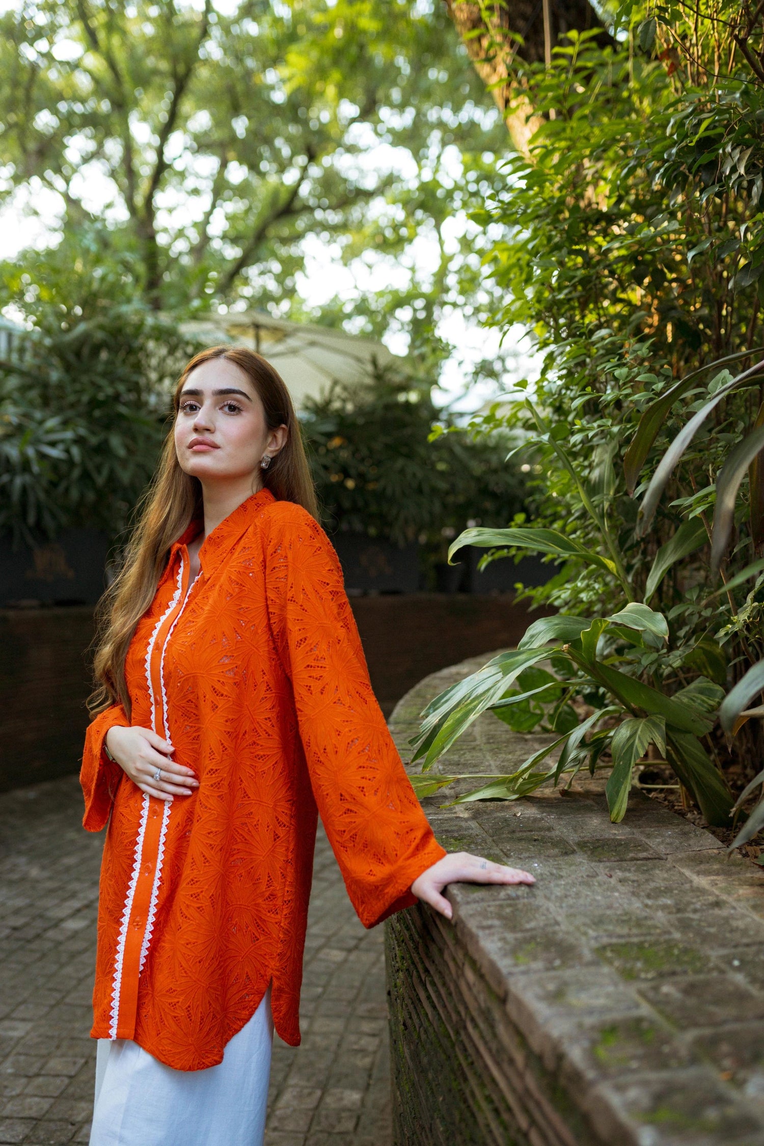 Stylish blunt orange short button-down shirt with a refined collar, contemporary round hem, and intricate lace along the buttons.
