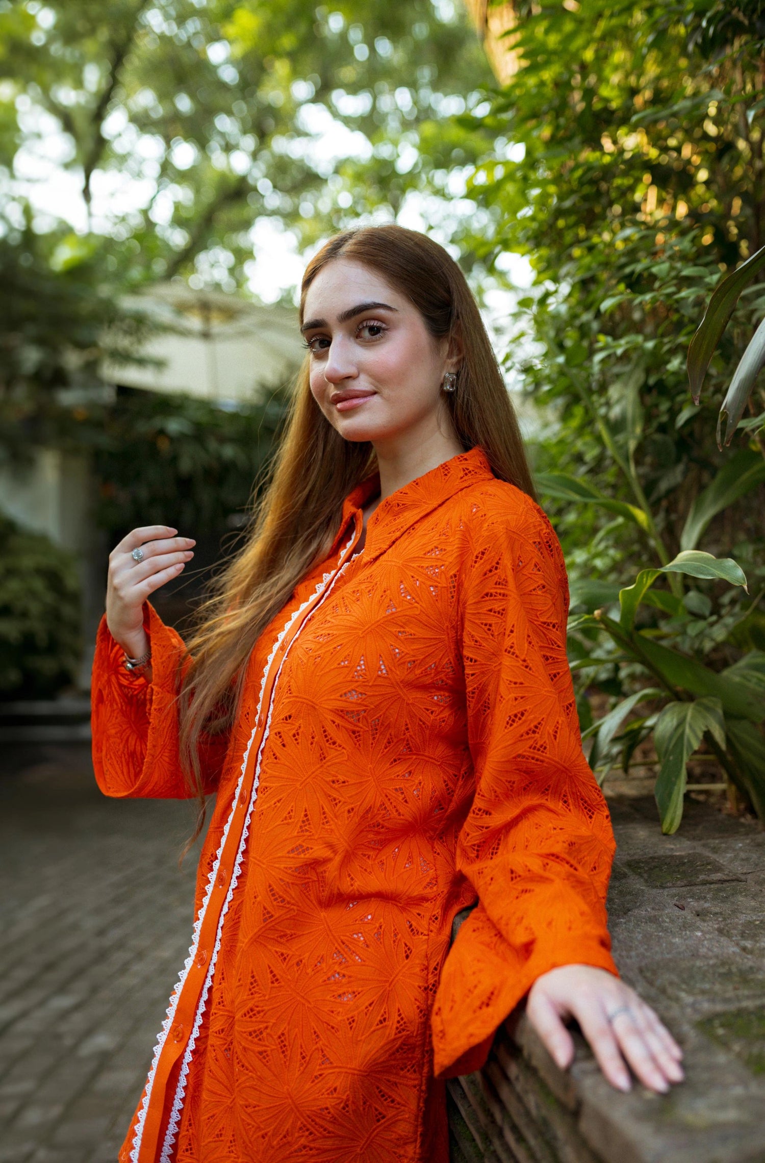 Stylish blunt orange short button-down shirt with a refined collar, contemporary round hem, and intricate lace along the buttons.