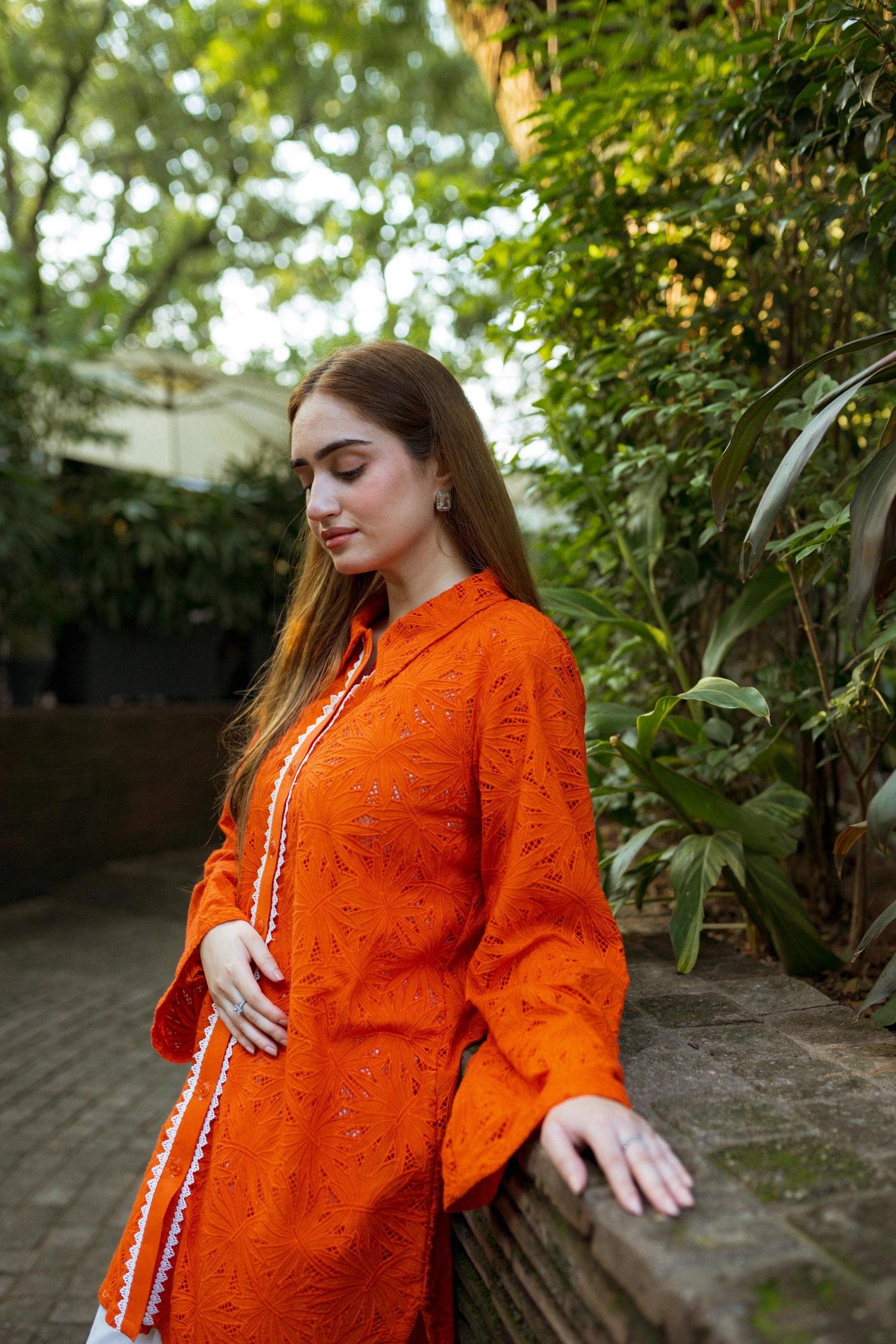 Stylish blunt orange short button-down shirt with a refined collar, contemporary round hem, and intricate lace along the buttons.