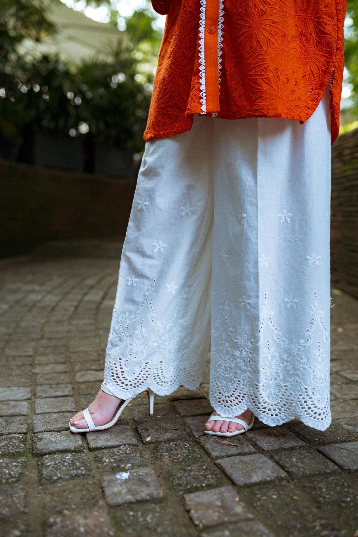 Stylish blunt orange short button-down shirt with a refined collar, contemporary round hem, and intricate lace along the buttons.