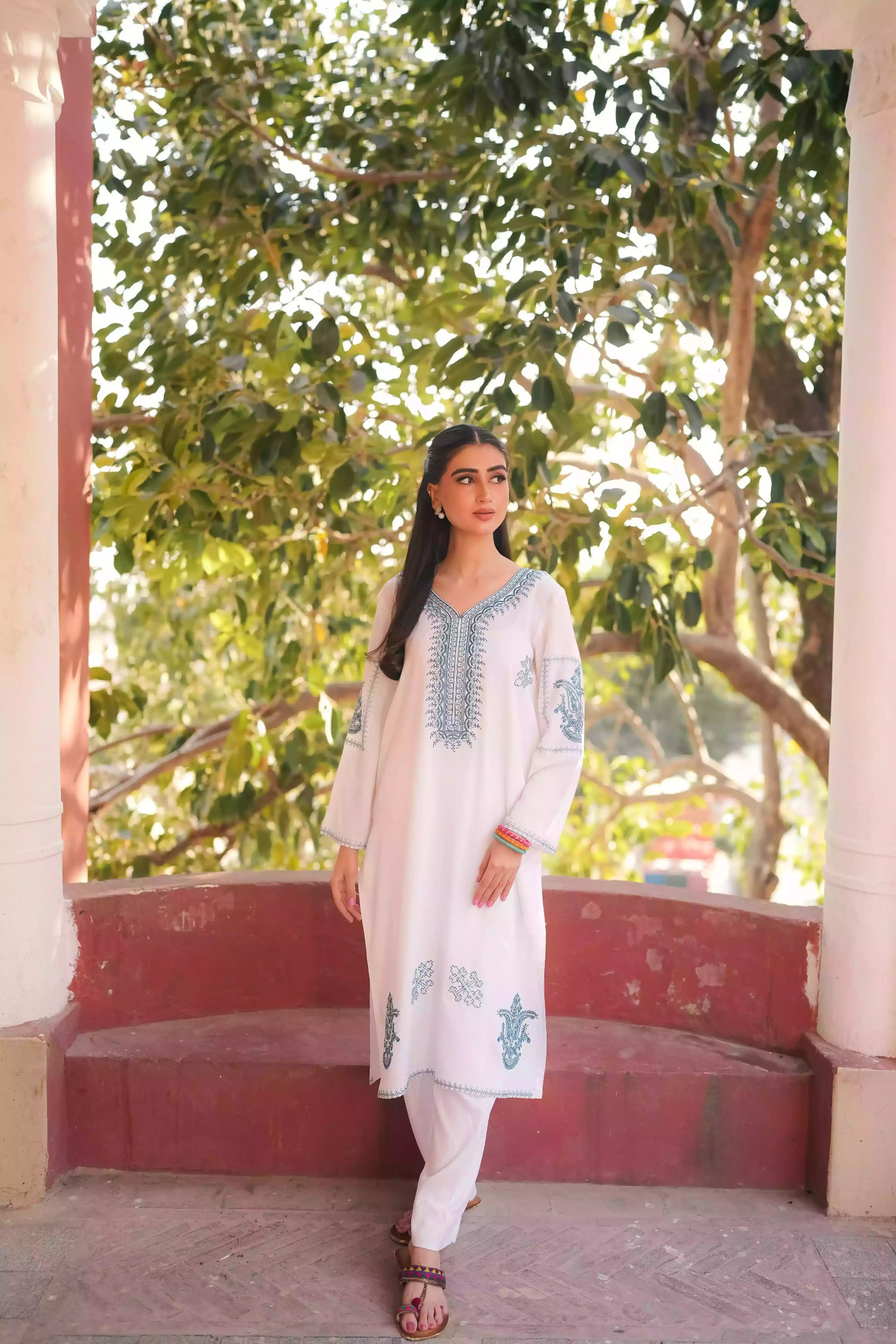 White outfit featuring delicate blue embroidery along the neckline, sleeves, and hem. Intricate motifs add depth and refinement, creating an elegant, serene look suitable for winter wear and festive gatherings.