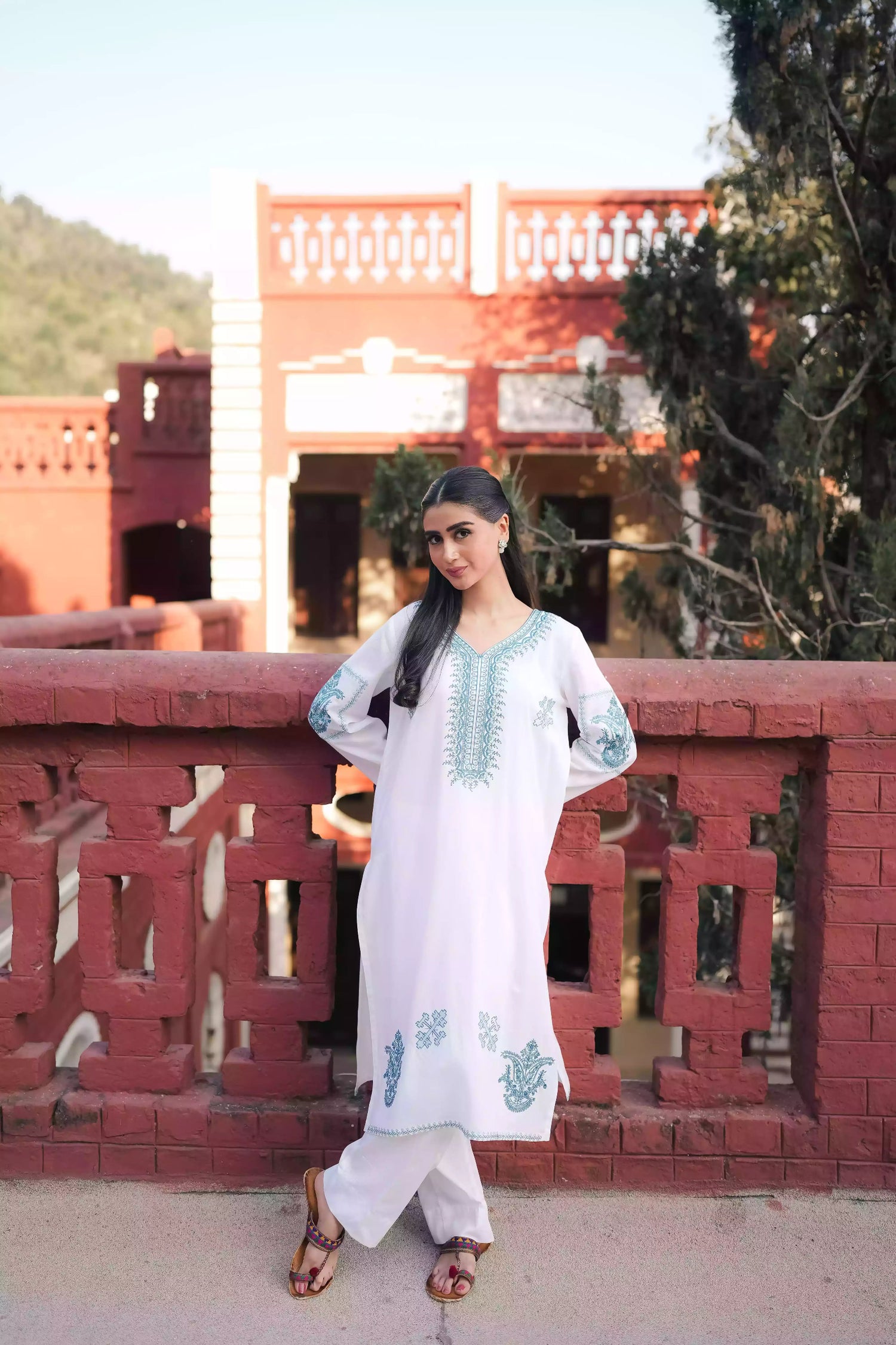 White outfit featuring delicate blue embroidery along the neckline, sleeves, and hem. Intricate motifs add depth and refinement, creating an elegant, serene look suitable for winter wear and festive gatherings.