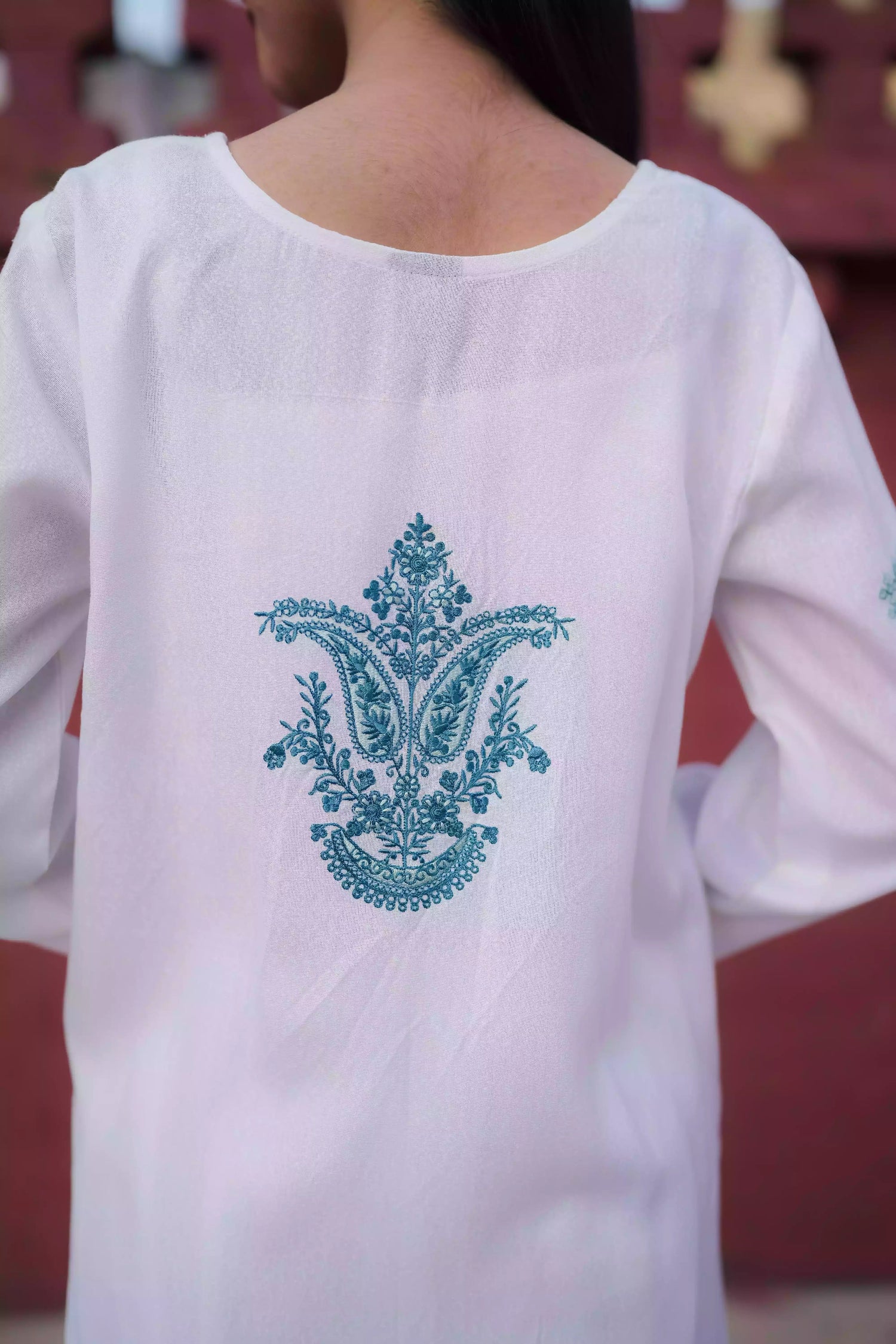White outfit featuring delicate blue embroidery along the neckline, sleeves, and hem. Intricate motifs add depth and refinement, creating an elegant, serene look suitable for winter wear and festive gatherings.