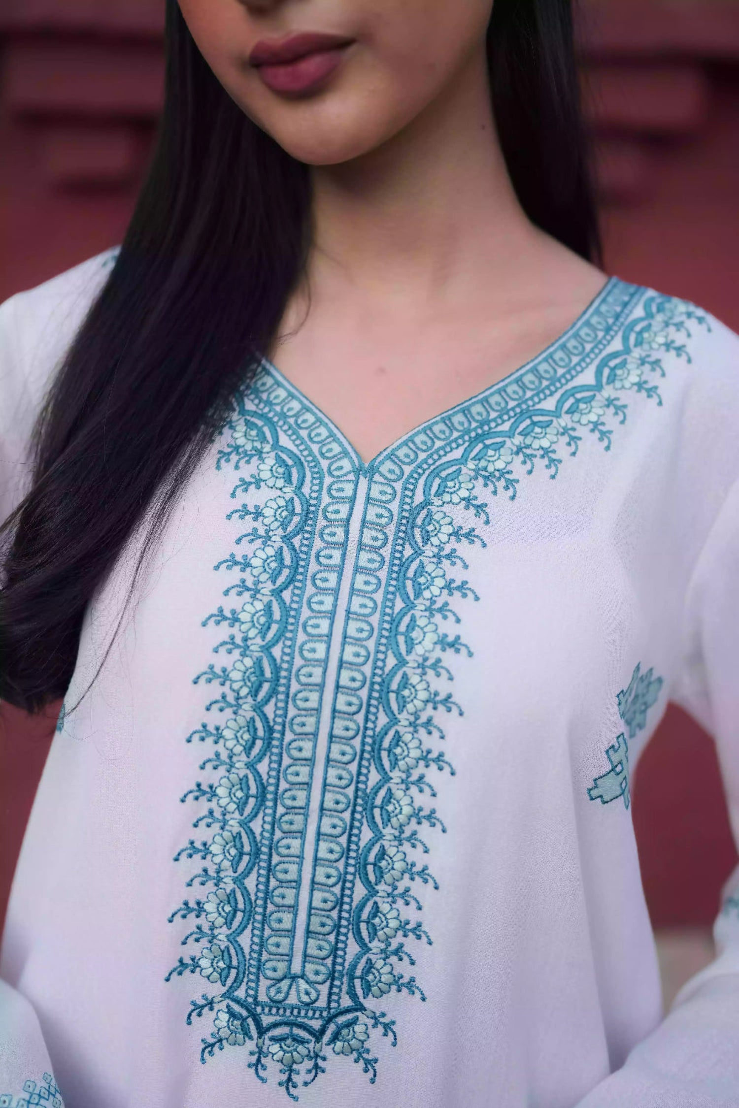 White outfit featuring delicate blue embroidery along the neckline, sleeves, and hem. Intricate motifs add depth and refinement, creating an elegant, serene look suitable for winter wear and festive gatherings.
