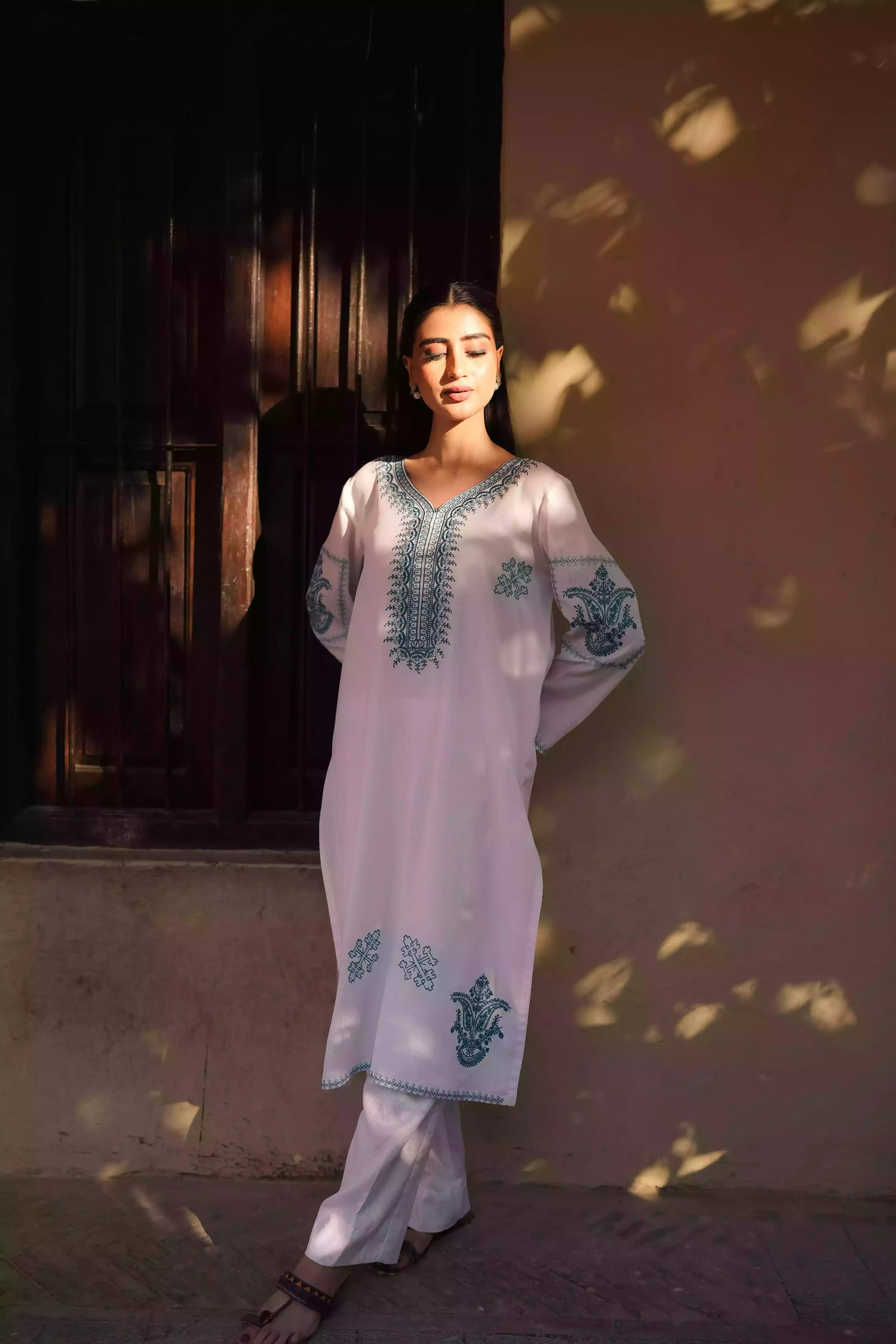 White outfit featuring delicate blue embroidery along the neckline, sleeves, and hem. Intricate motifs add depth and refinement, creating an elegant, serene look suitable for winter wear and festive gatherings.