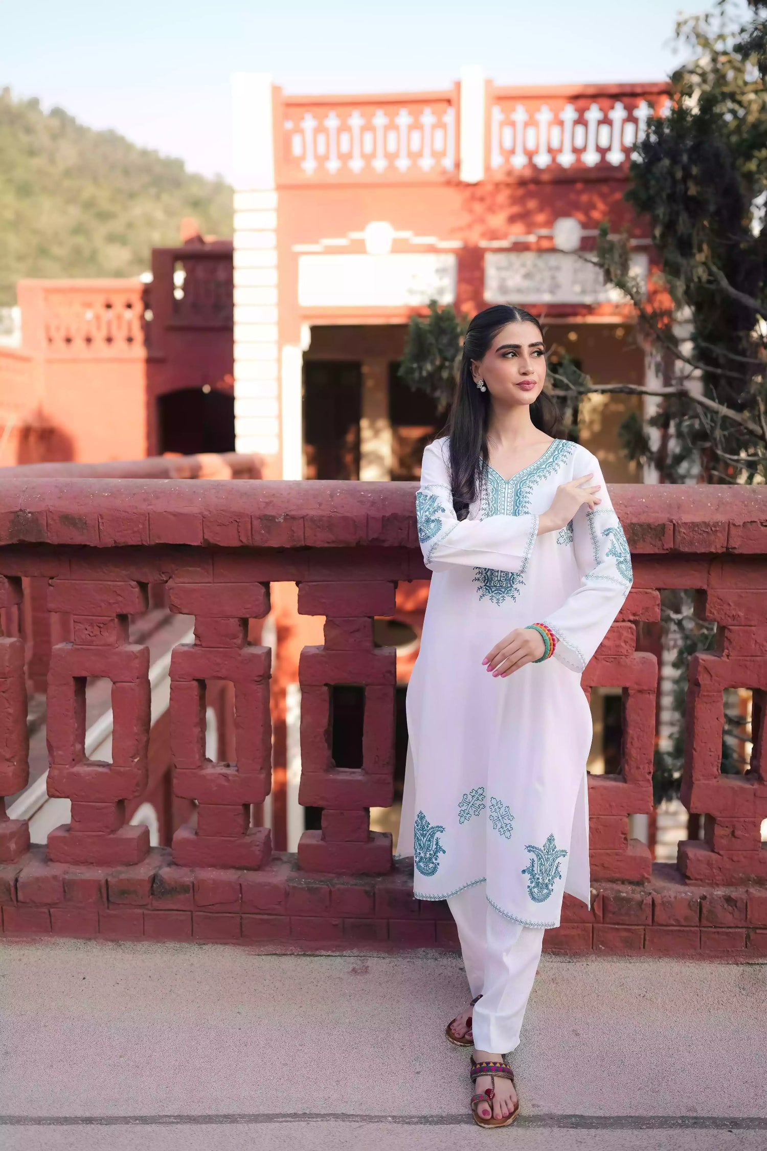 White outfit featuring delicate blue embroidery along the neckline, sleeves, and hem. Intricate motifs add depth and refinement, creating an elegant, serene look suitable for winter wear and festive gatherings.