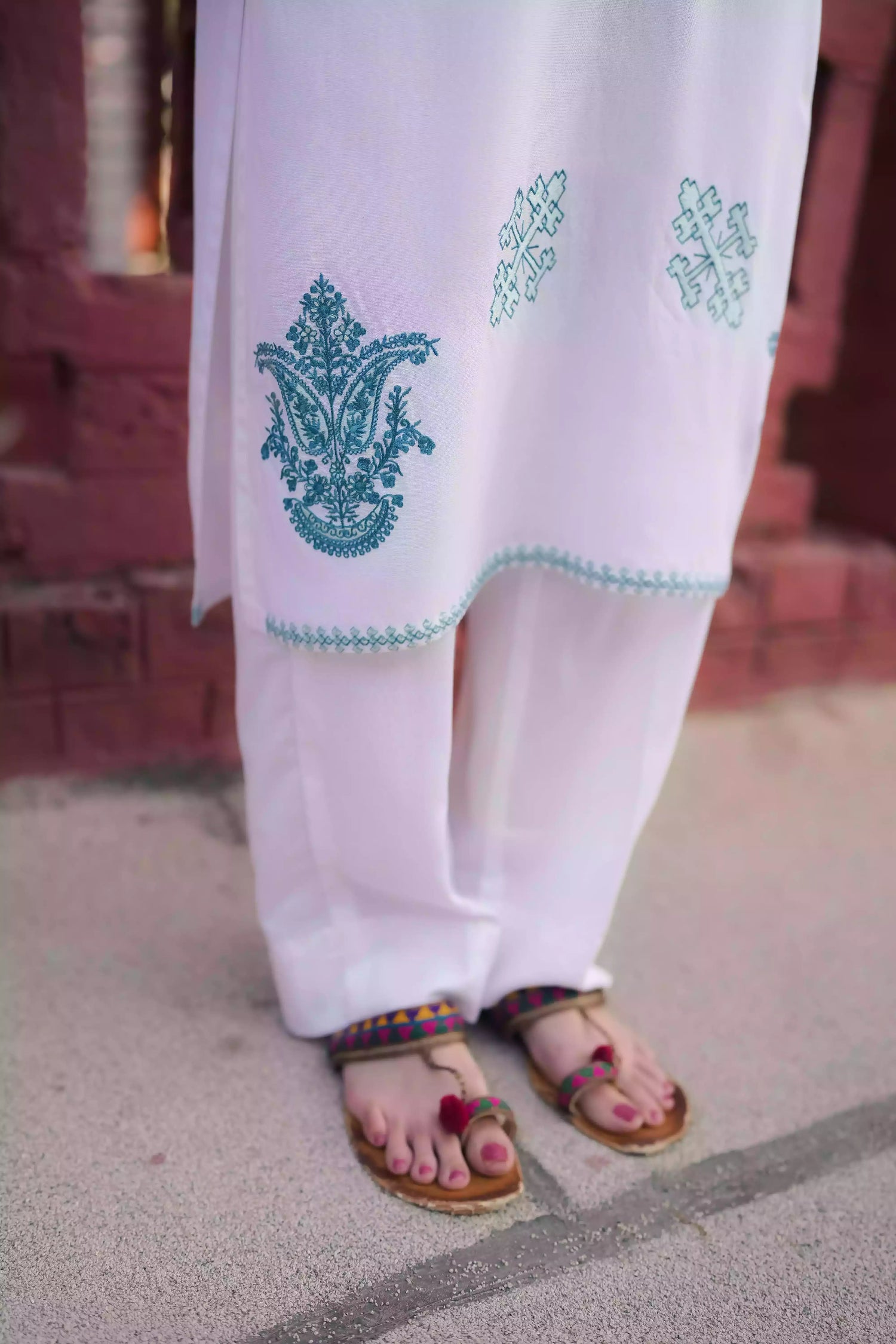 White outfit featuring delicate blue embroidery along the neckline, sleeves, and hem. Intricate motifs add depth and refinement, creating an elegant, serene look suitable for winter wear and festive gatherings.