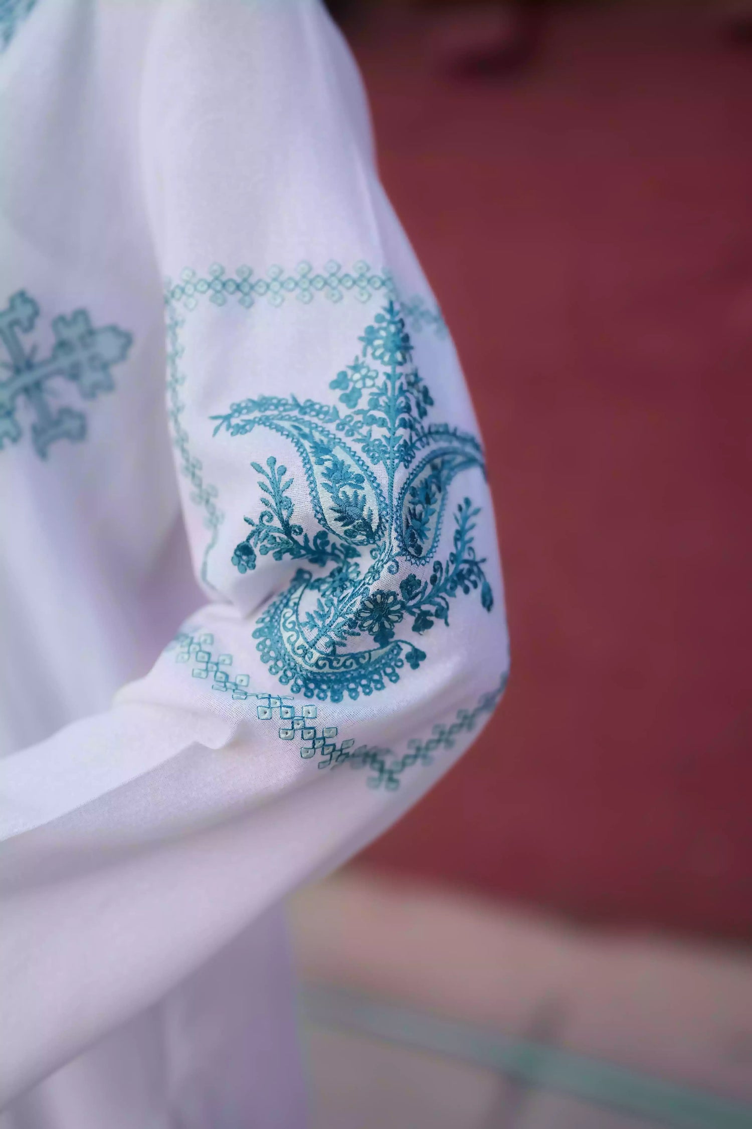 White outfit featuring delicate blue embroidery along the neckline, sleeves, and hem. Intricate motifs add depth and refinement, creating an elegant, serene look suitable for winter wear and festive gatherings.