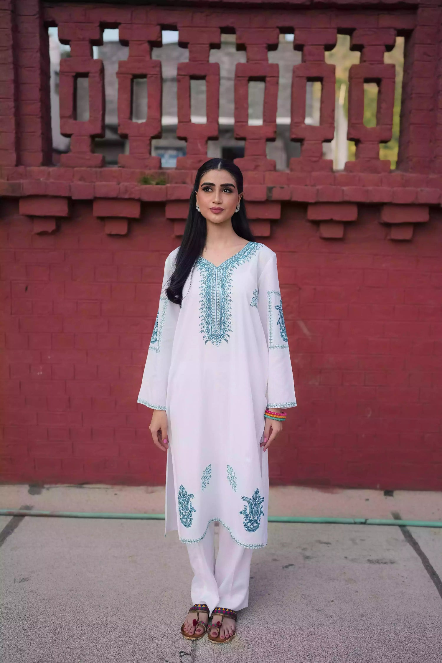 White outfit featuring delicate blue embroidery along the neckline, sleeves, and hem. Intricate motifs add depth and refinement, creating an elegant, serene look suitable for winter wear and festive gatherings.