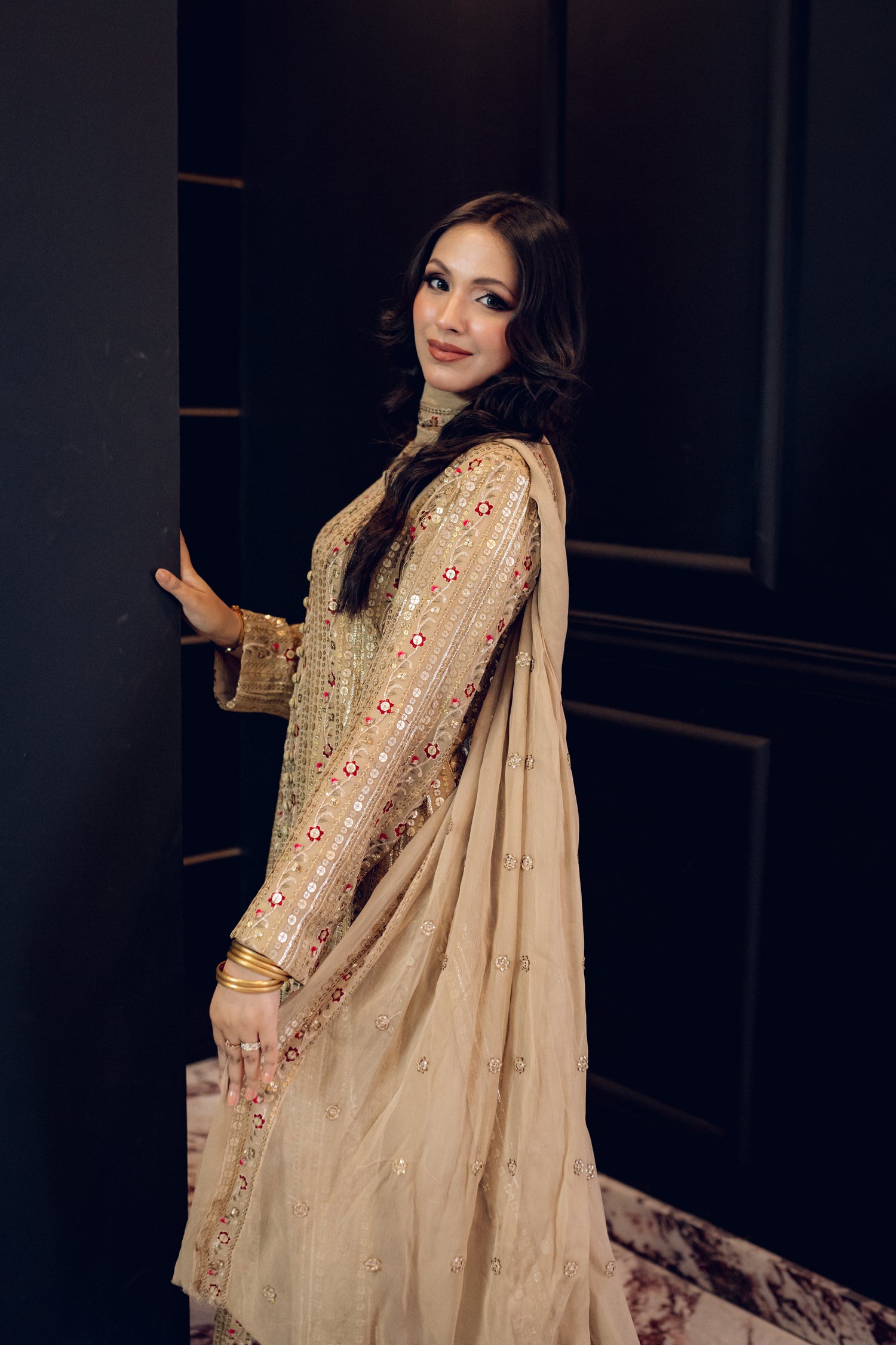 A luxurious and sophisticated dress featuring golden sequin shimmer, intricate multithread embroidery, refined buttons, a chiffon dupatta with embroidered borders and sequins, and flared raw silk pants—perfect for making a statement at special occasions.