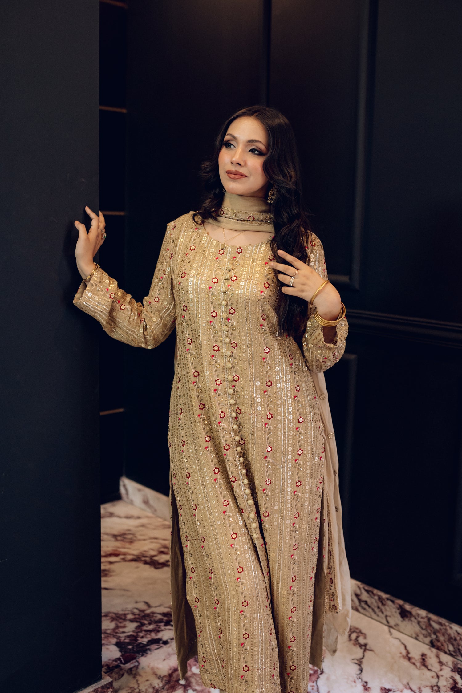 A luxurious and sophisticated dress featuring golden sequin shimmer, intricate multithread embroidery, refined buttons, a chiffon dupatta with embroidered borders and sequins, and flared raw silk pants—perfect for making a statement at special occasions.