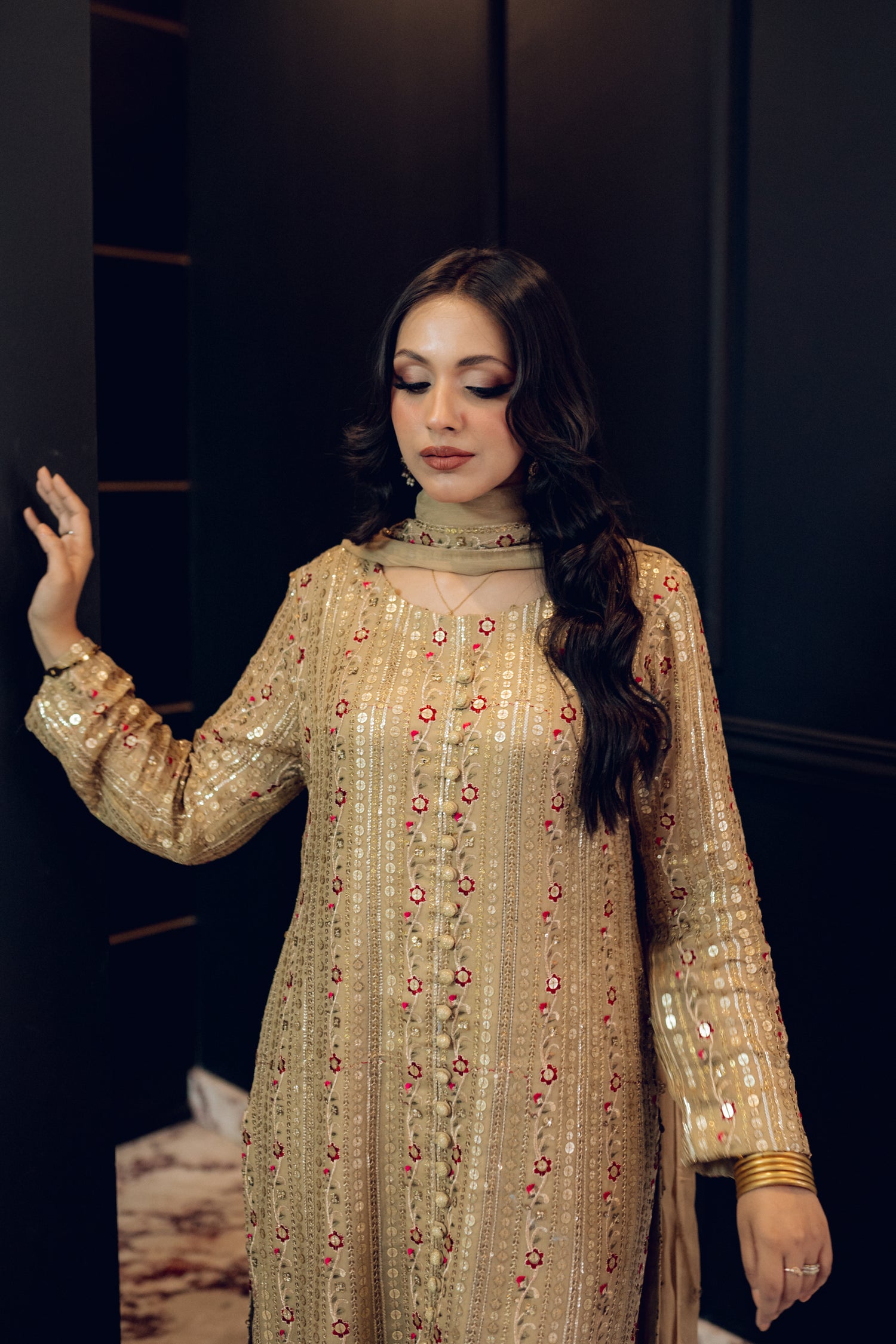 A luxurious and sophisticated dress featuring golden sequin shimmer, intricate multithread embroidery, refined buttons, a chiffon dupatta with embroidered borders and sequins, and flared raw silk pants—perfect for making a statement at special occasions.