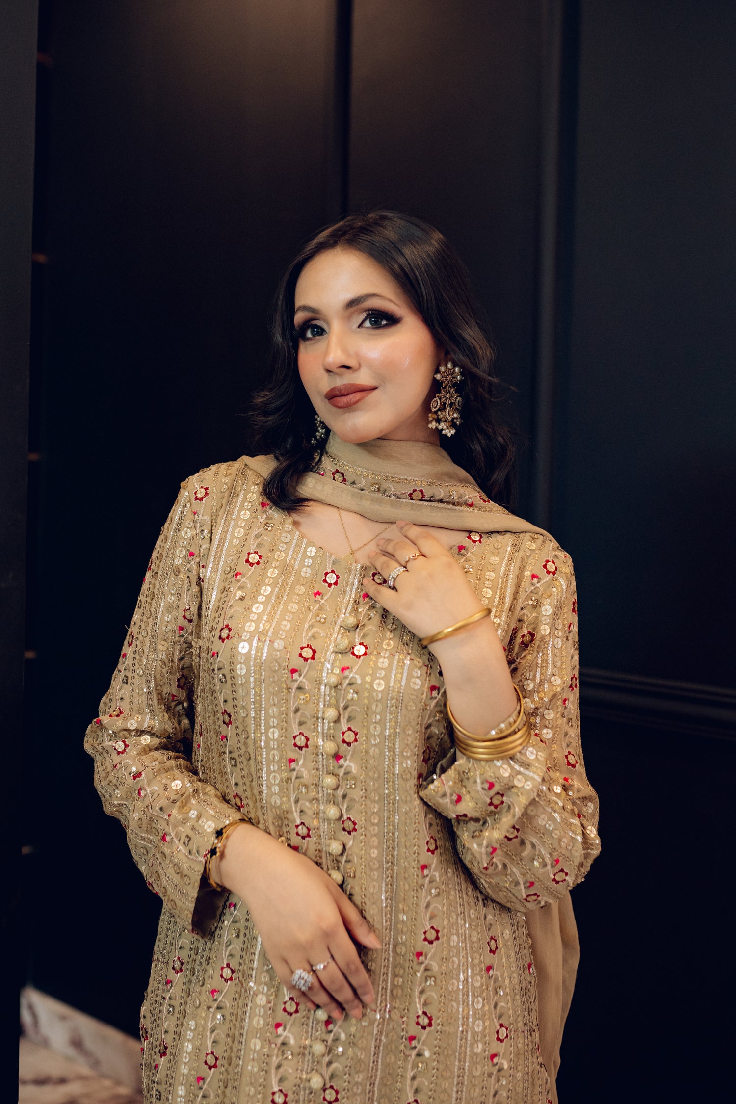 A luxurious and sophisticated dress featuring golden sequin shimmer, intricate multithread embroidery, refined buttons, a chiffon dupatta with embroidered borders and sequins, and flared raw silk pants—perfect for making a statement at special occasions.