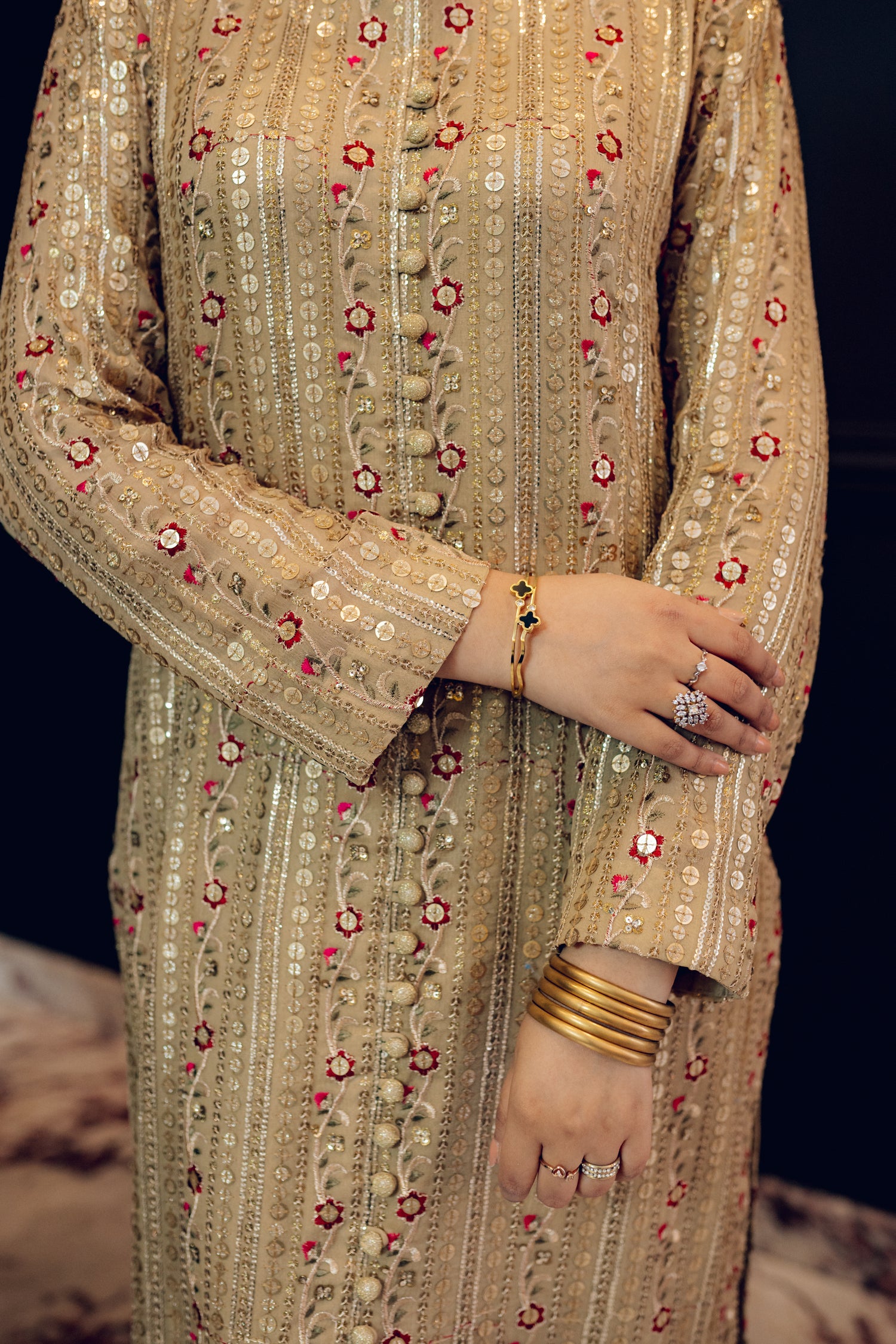 A luxurious and sophisticated dress featuring golden sequin shimmer, intricate multithread embroidery, refined buttons, a chiffon dupatta with embroidered borders and sequins, and flared raw silk pants—perfect for making a statement at special occasions.