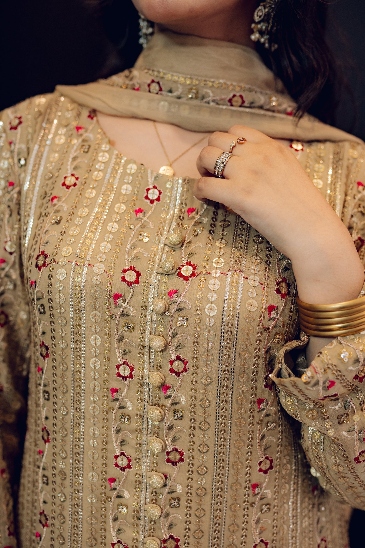A luxurious and sophisticated dress featuring golden sequin shimmer, intricate multithread embroidery, refined buttons, a chiffon dupatta with embroidered borders and sequins, and flared raw silk pants—perfect for making a statement at special occasions.