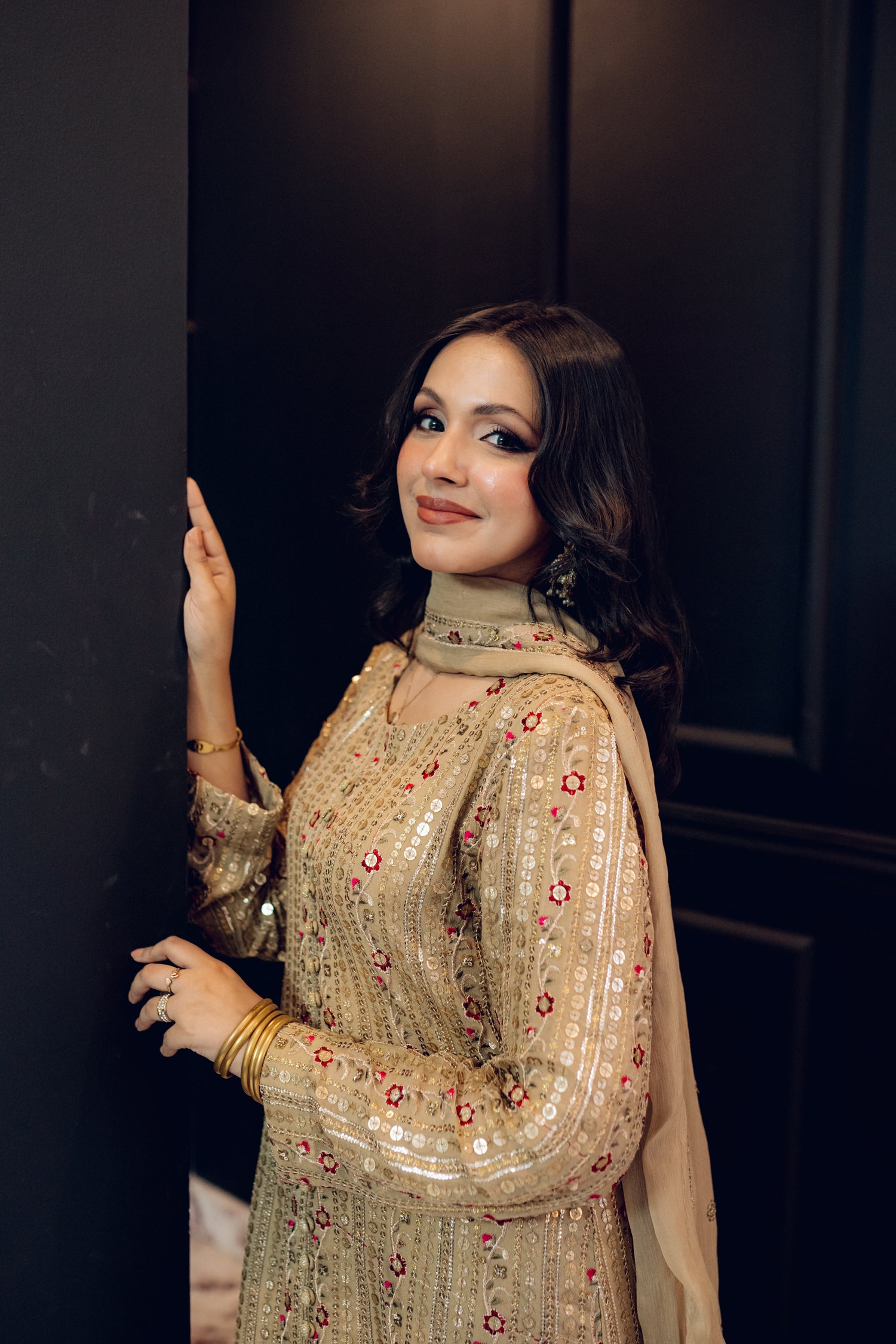 A luxurious and sophisticated dress featuring golden sequin shimmer, intricate multithread embroidery, refined buttons, a chiffon dupatta with embroidered borders and sequins, and flared raw silk pants—perfect for making a statement at special occasions.