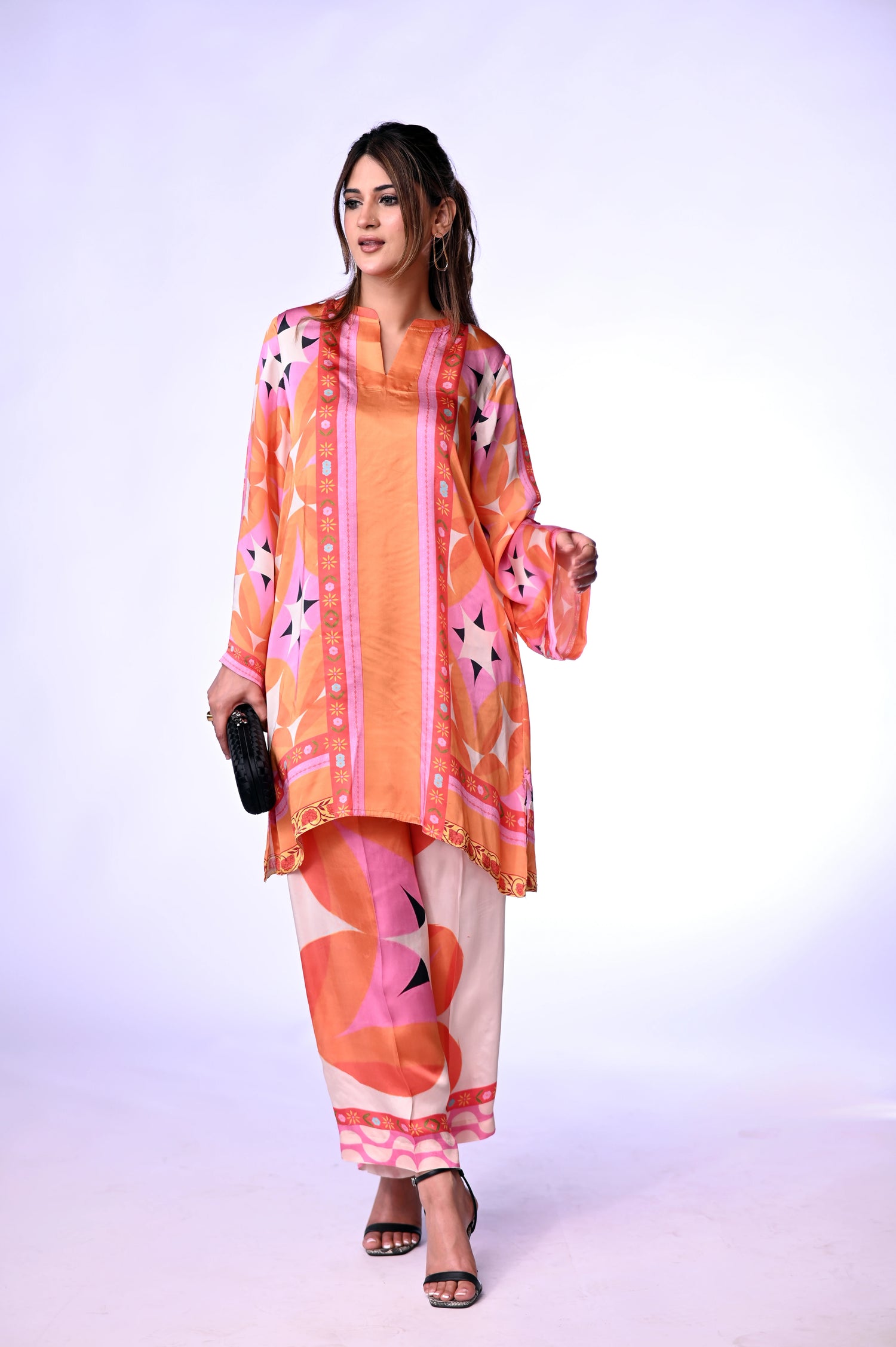 Vibrant orange silk cord set with bold circle patterns, combining fluid elegance and high-fashion comfort.