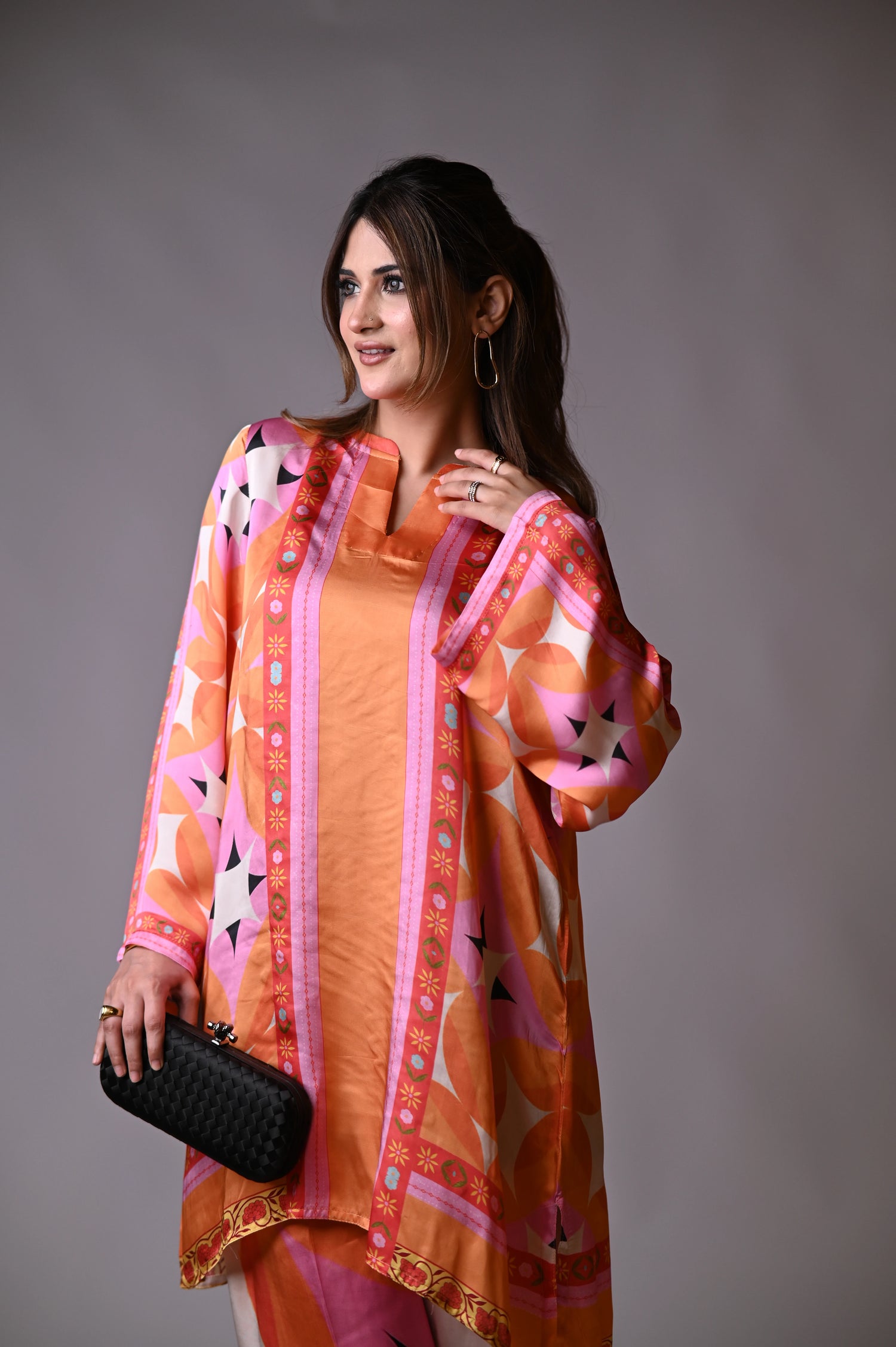 Vibrant orange silk cord set with bold circle patterns, combining fluid elegance and high-fashion comfort.