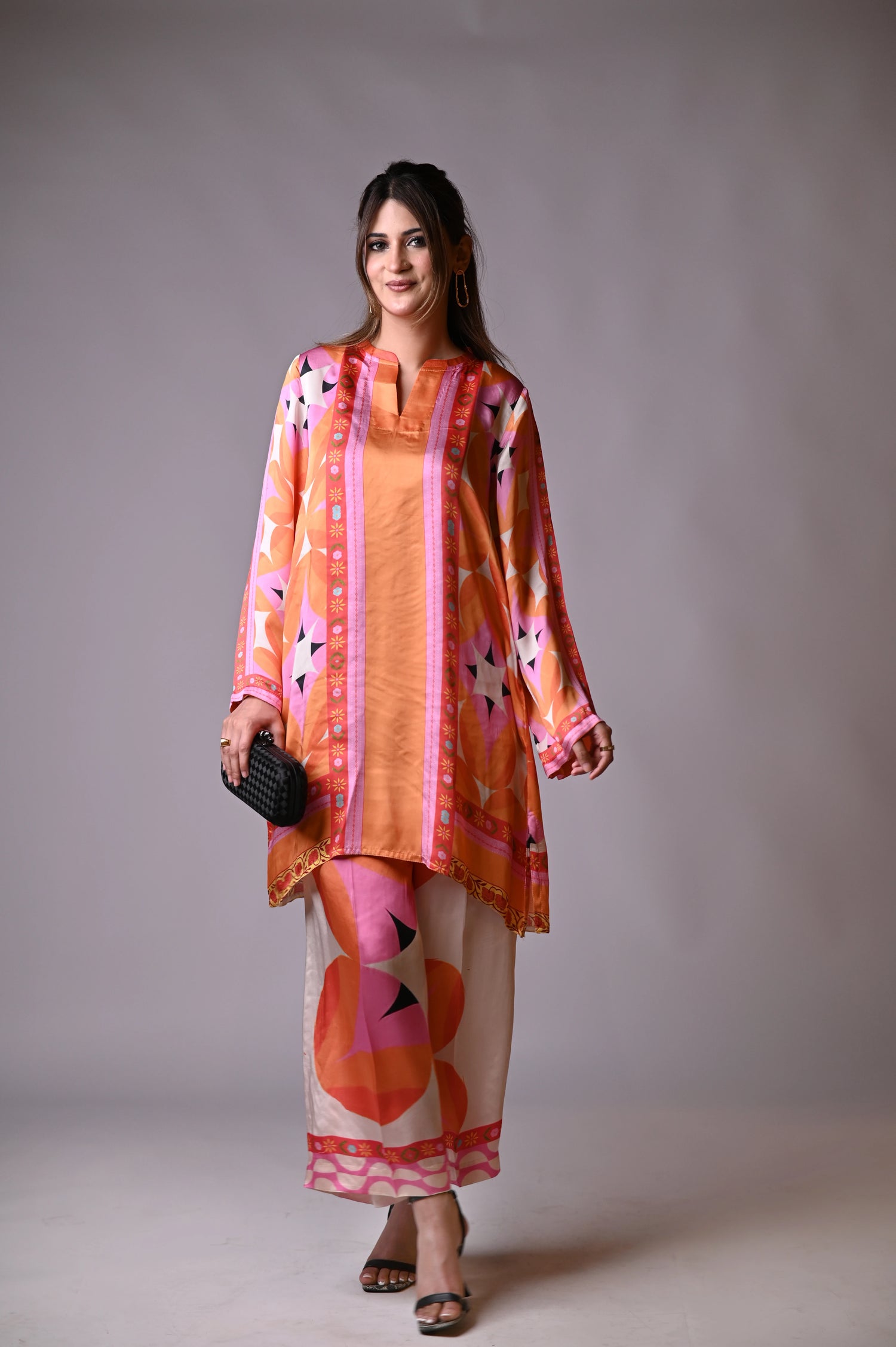 Vibrant orange silk cord set with bold circle patterns, combining fluid elegance and high-fashion comfort.