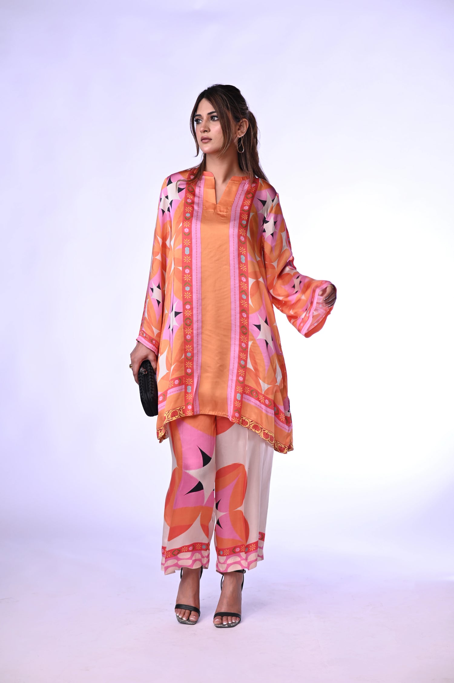 Vibrant orange silk cord set with bold circle patterns, combining fluid elegance and high-fashion comfort.