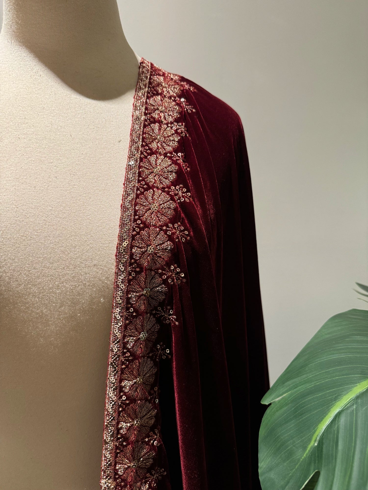Exquisite deep maroon velvet shawl with wide antique gold tilla embroidery and sequins forming intricate floral motifs along scalloped edges, perfect for formal winter occasions.