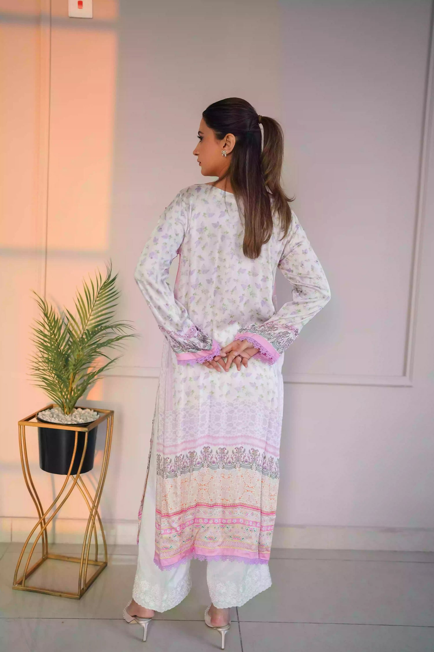 A luminous white kurta adorned with delicate lilac florals and subtle leafy accents. Fine detailing at the neckline adds understated opulence, while ornamental borders lead into a softly scalloped lilac edge. This piece feel effortlessly refined for daytime celebrations, Eid or elegant evening wear.