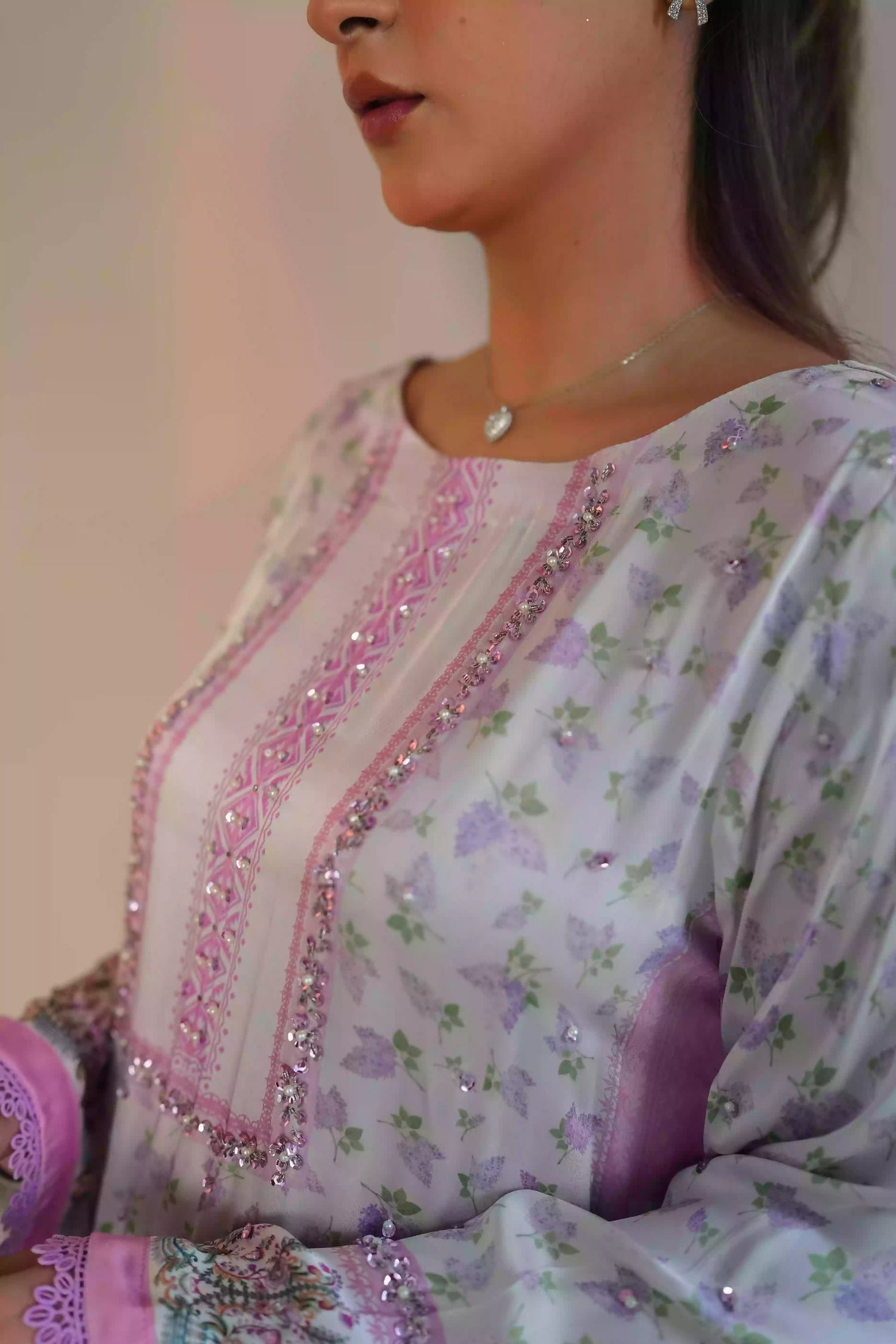 A luminous white kurta adorned with delicate lilac florals and subtle leafy accents. Fine detailing at the neckline adds understated opulence, while ornamental borders lead into a softly scalloped lilac edge. This piece feel effortlessly refined for daytime celebrations, Eid or elegant evening wear.