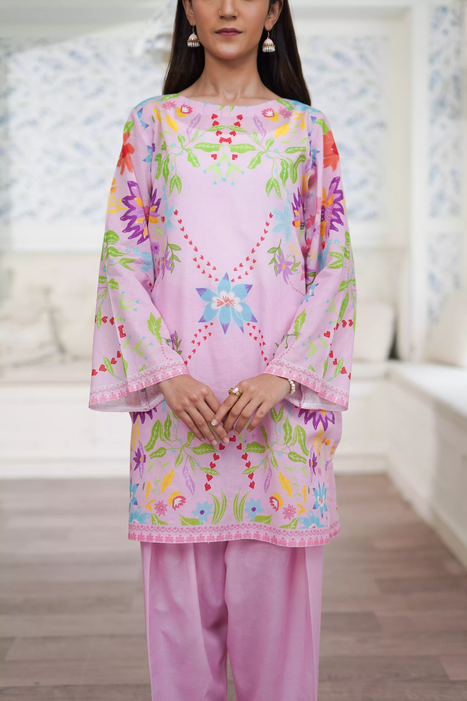 Blush pink cord set featuring a straight-cut shirt with symmetrical wildflower and botanical prints, paired with plain pink trousers, adds elegance to this minimalist floral ensemble.