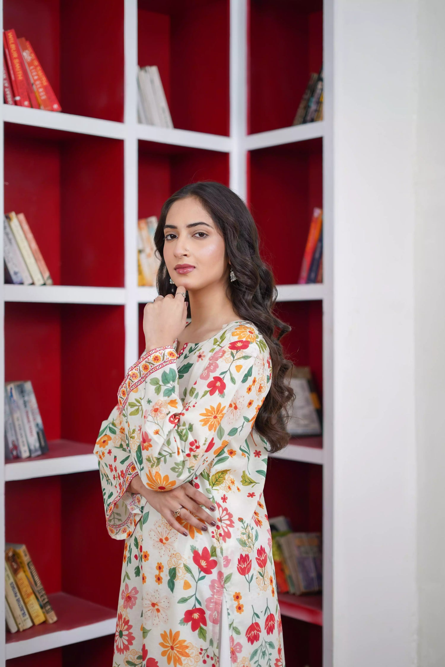 A printed kurta with vibrant red, mustard, and green tones of florals and a striking border. Paired with white scalloped lace trousers. 