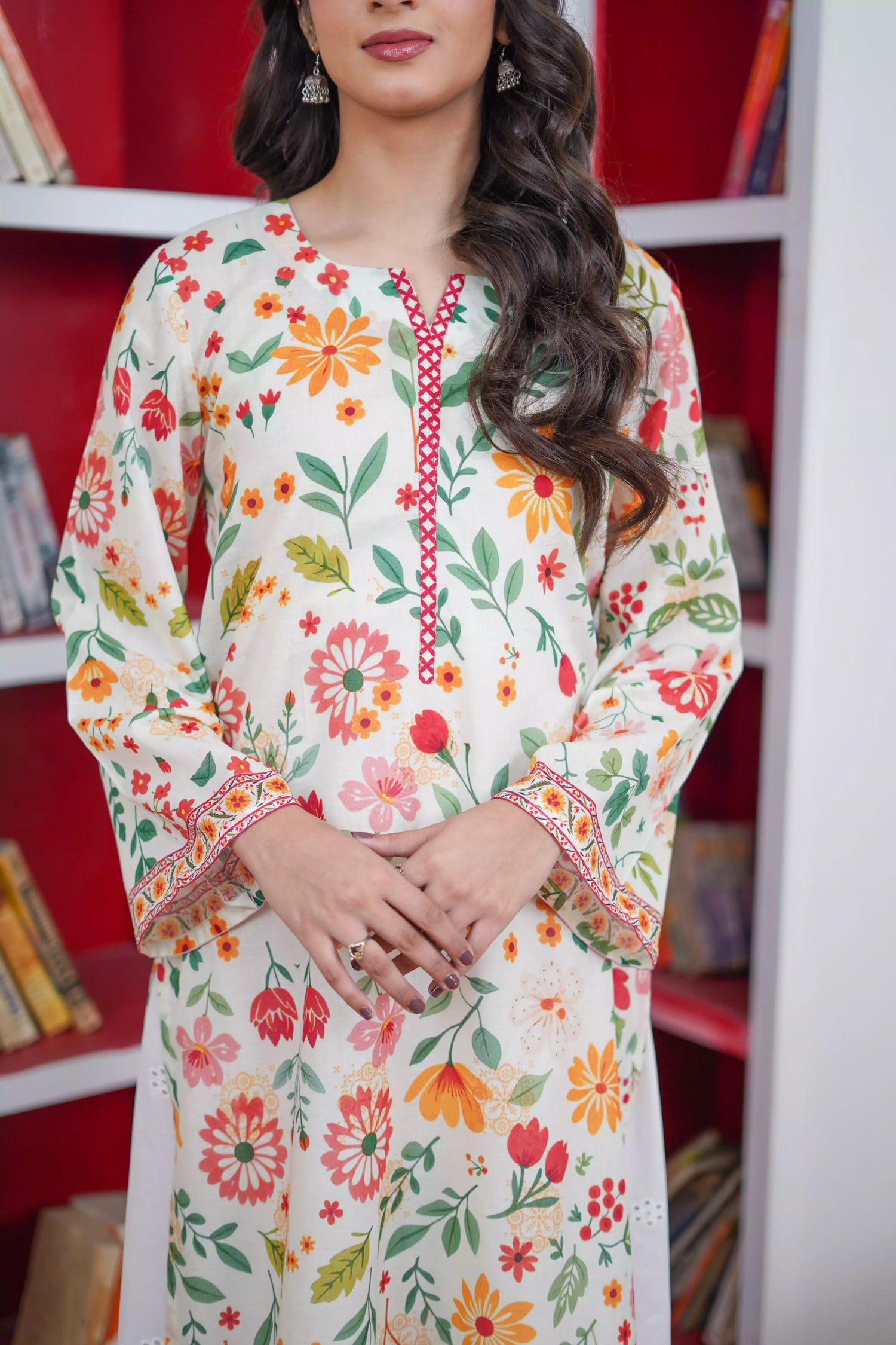 A printed kurta with vibrant red, mustard, and green tones of florals and a striking border. Paired with white scalloped lace trousers. 