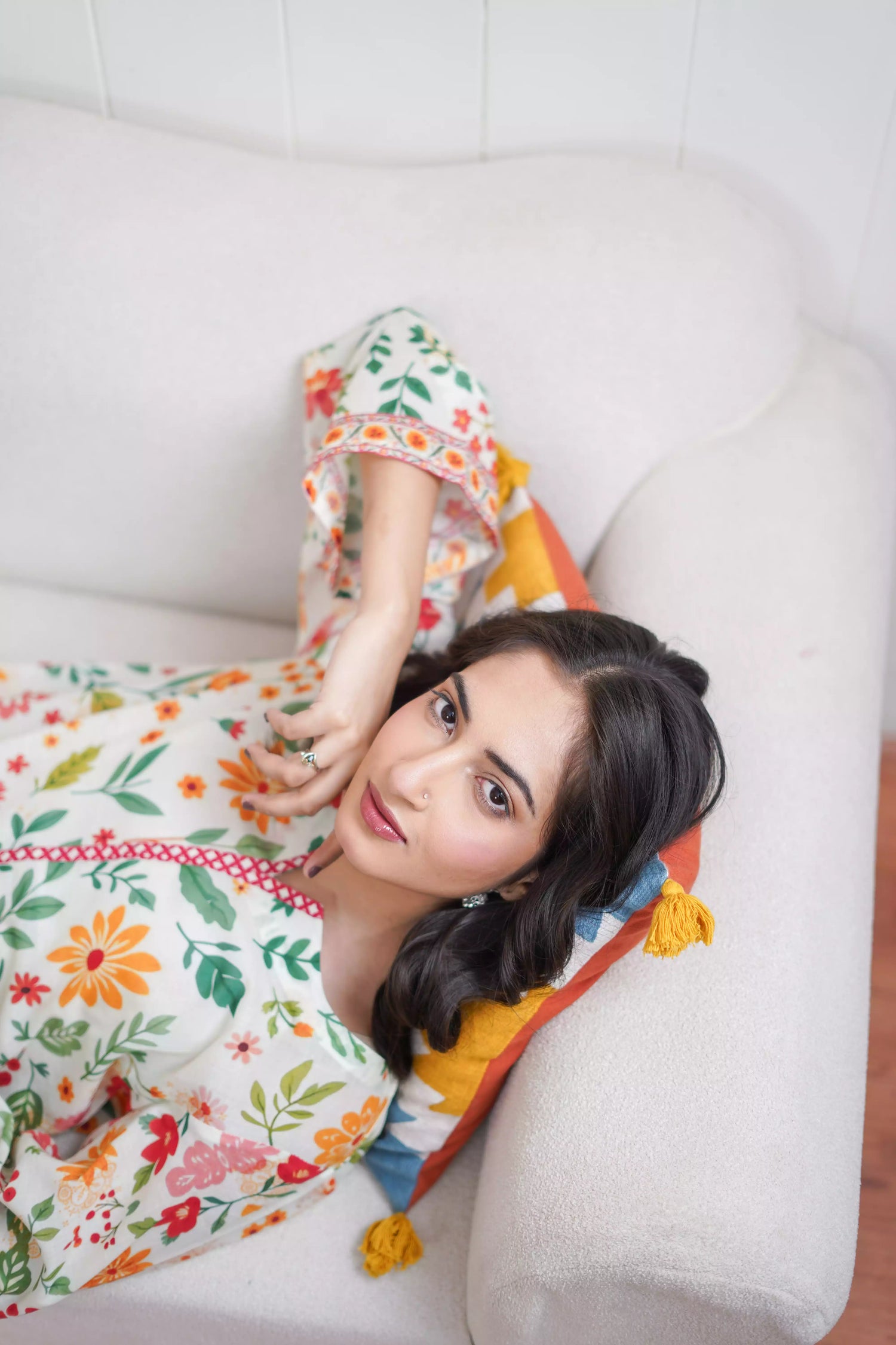 A printed kurta with vibrant red, mustard, and green tones of florals and a striking border. Paired with white scalloped lace trousers. 