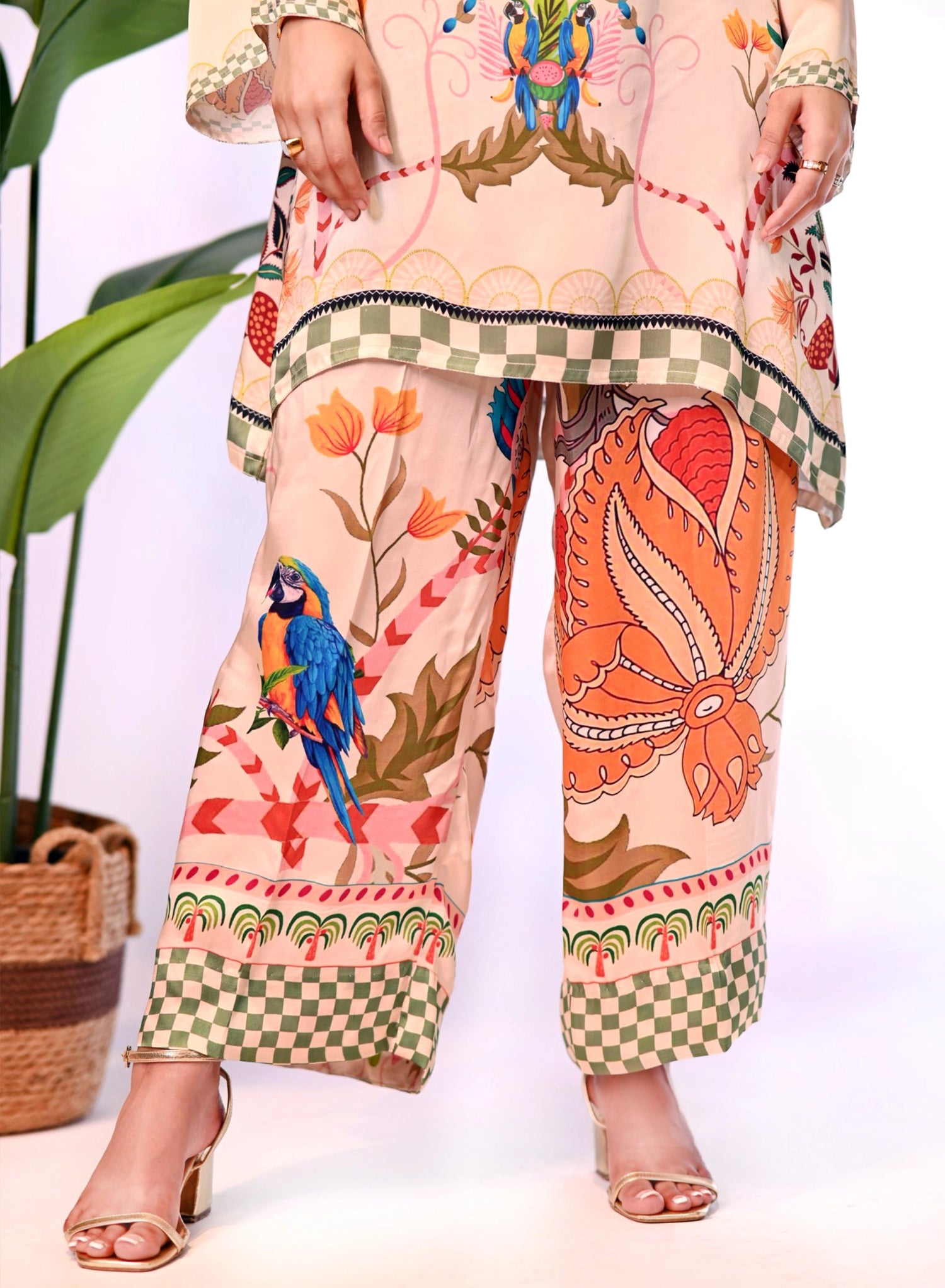Cord Set in skin gold silk featuring a long tunic with a structured high neckline and full sleeves. Paired with wide-leg culotte pants, both pieces are adorned with colorful botanical motifs.
