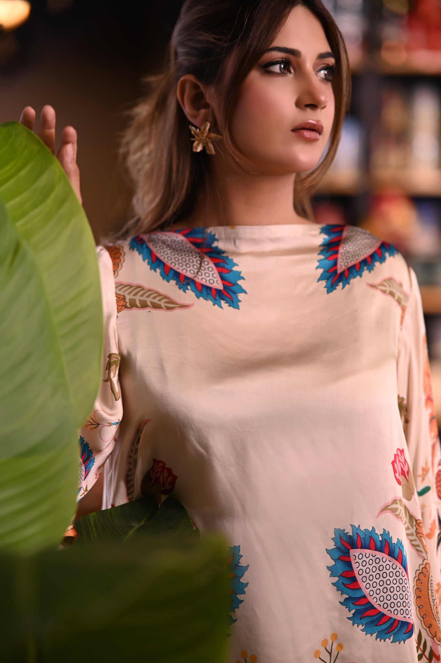 Cord Set in skin gold silk featuring a long tunic with a structured high neckline and full sleeves. Paired with wide-leg culotte pants, both pieces are adorned with colorful botanical motifs.