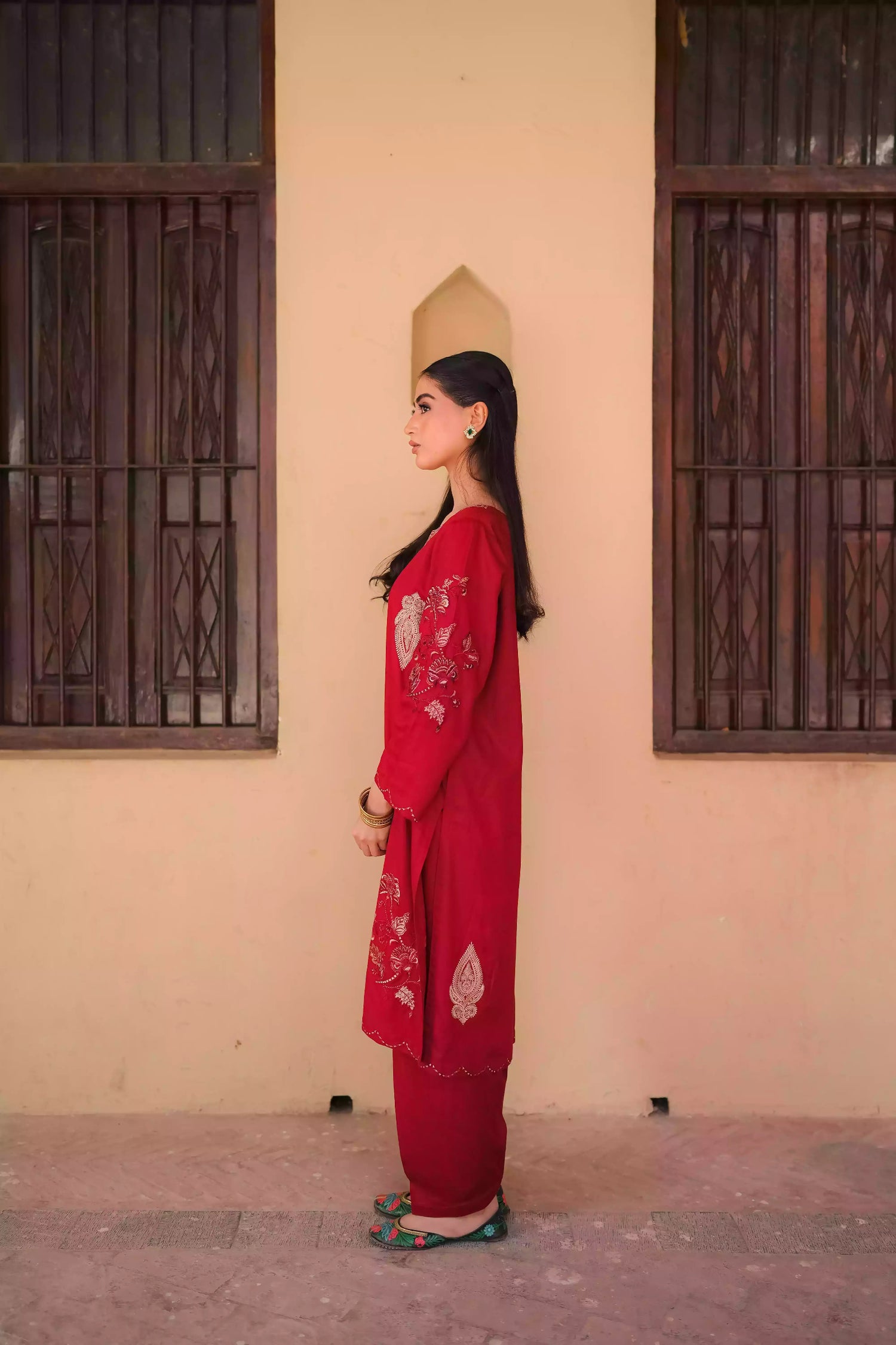 An embroidered suit with delicate motifs and subtle threadwork along the borders. The look is paired with a beautifully adorned trouser accented with a rich hint of red, creating a warm, festive appearance ideal for celebrations and winter gatherings.