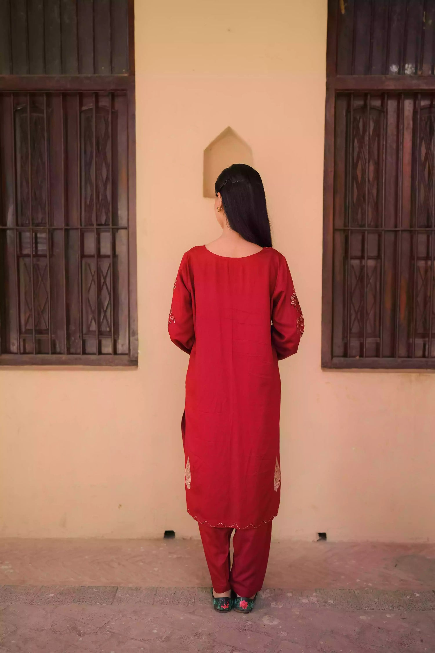 An embroidered suit with delicate motifs and subtle threadwork along the borders. The look is paired with a beautifully adorned trouser accented with a rich hint of red, creating a warm, festive appearance ideal for celebrations and winter gatherings.