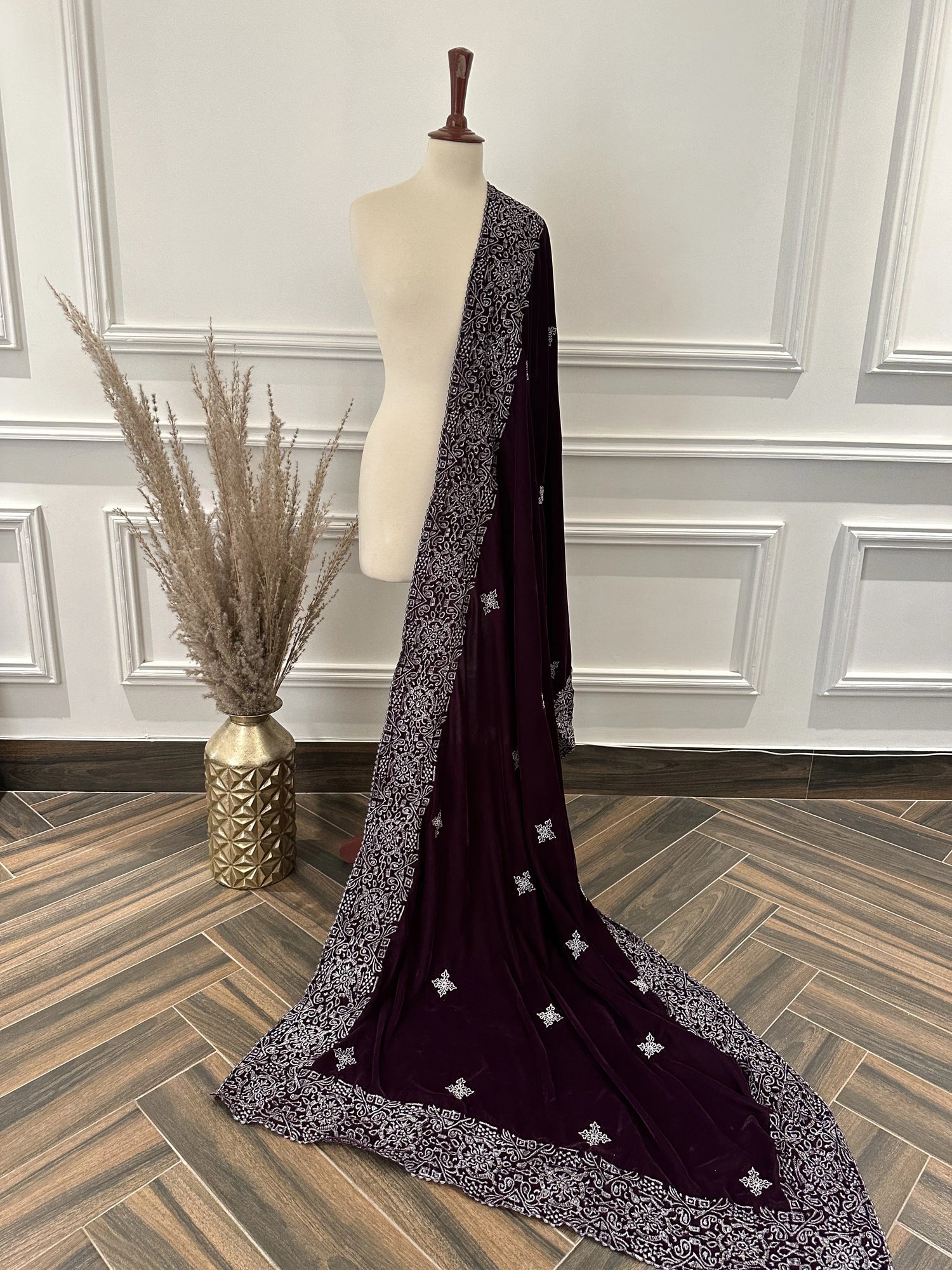 Rich deep plum velvet shawl with a smooth, lustrous finish, detailed with elaborate silver tilla embroidery. The shawl features a bold ornamental border of floral motifs across the body and finished with graceful border edges, making it a refined choice for formal occasions.