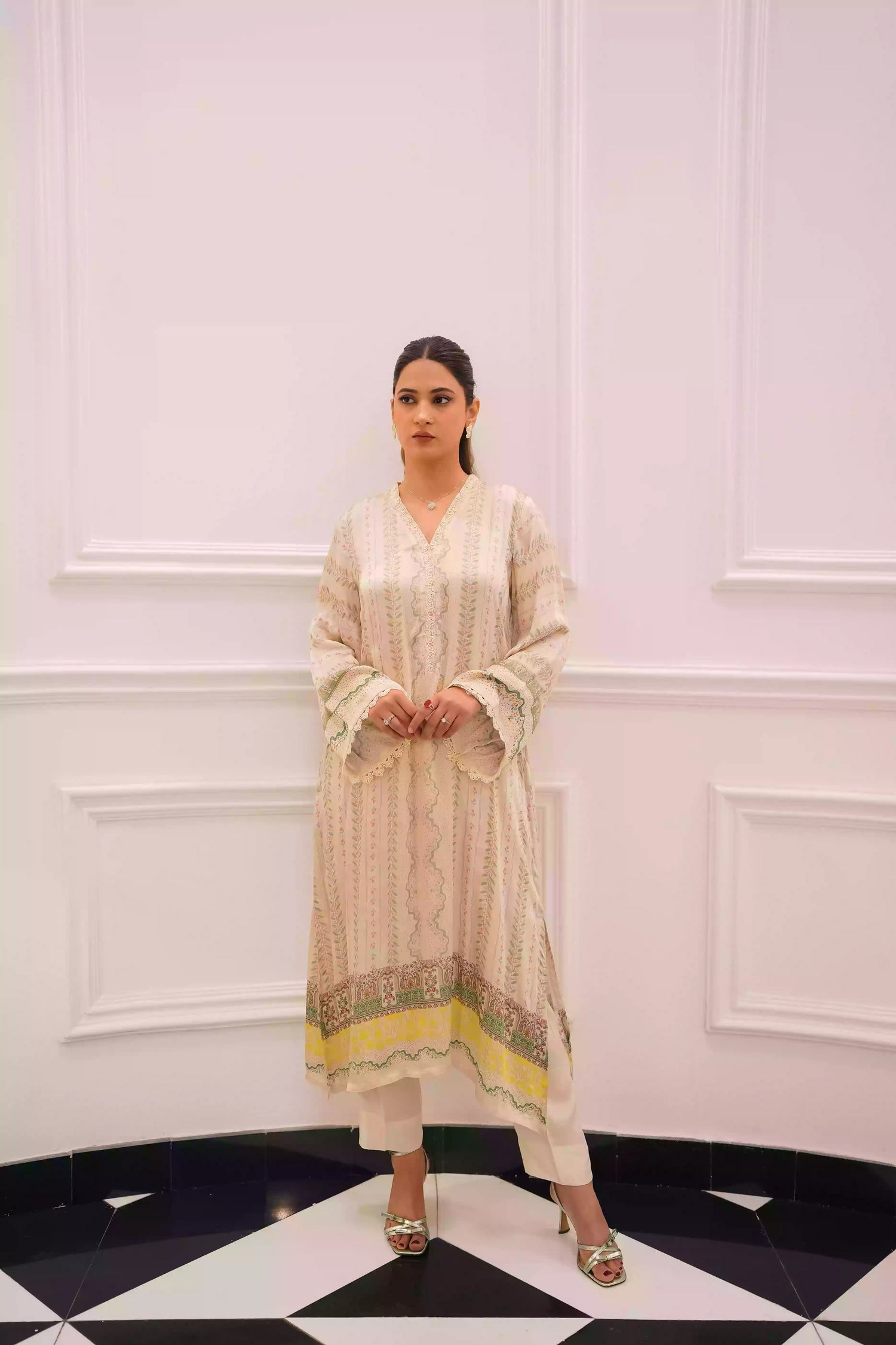 Elegant creamy ivory kameez adorned with delicate vertical floral trails, creating an elongated, graceful silhouette. Intricate lace inserts and subtle embellishments highlight the neckline, while wide, airy sleeves are finished with scalloped edges making this elegant piece ideal for daytime gatherings or refined evening events.