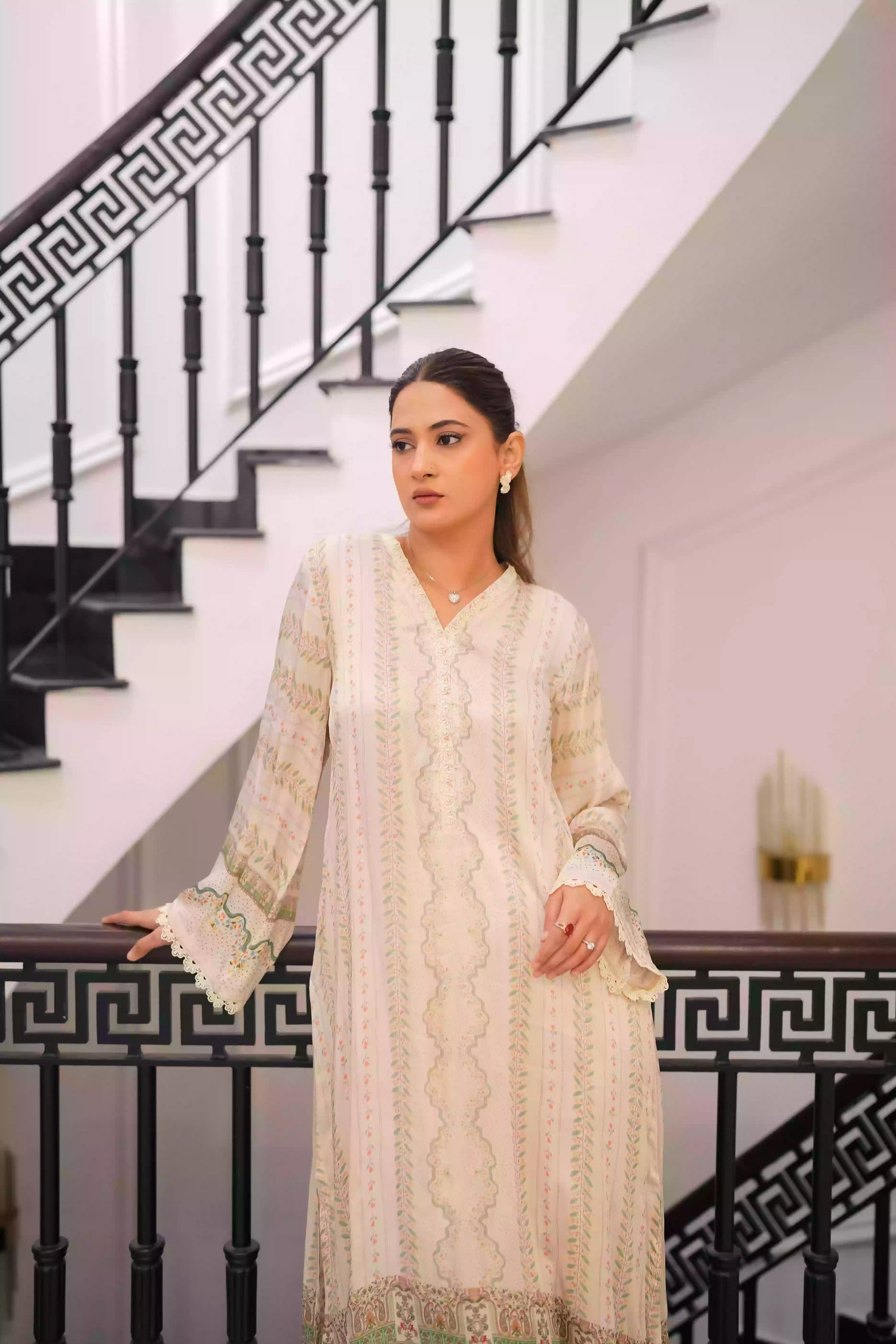 Elegant creamy ivory kameez adorned with delicate vertical floral trails, creating an elongated, graceful silhouette. Intricate lace inserts and subtle embellishments highlight the neckline, while wide, airy sleeves are finished with scalloped edges making this elegant piece ideal for daytime gatherings or refined evening events.