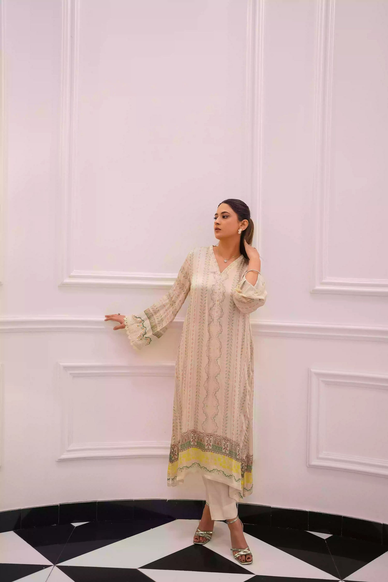 Elegant creamy ivory kameez adorned with delicate vertical floral trails, creating an elongated, graceful silhouette. Intricate lace inserts and subtle embellishments highlight the neckline, while wide, airy sleeves are finished with scalloped edges making this elegant piece ideal for daytime gatherings or refined evening events.