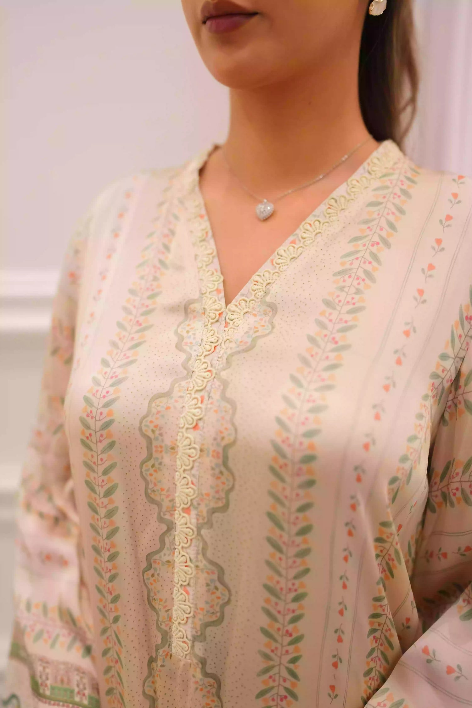 Elegant creamy ivory kameez adorned with delicate vertical floral trails, creating an elongated, graceful silhouette. Intricate lace inserts and subtle embellishments highlight the neckline, while wide, airy sleeves are finished with scalloped edges making this elegant piece ideal for daytime gatherings or refined evening events.