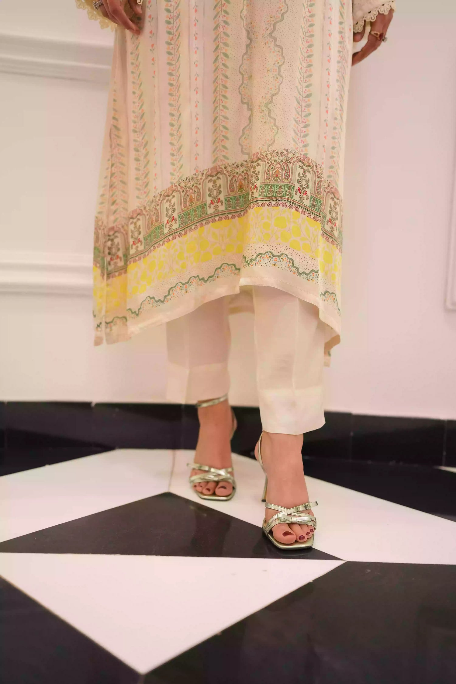 Elegant creamy ivory kameez adorned with delicate vertical floral trails, creating an elongated, graceful silhouette. Intricate lace inserts and subtle embellishments highlight the neckline, while wide, airy sleeves are finished with scalloped edges making this elegant piece ideal for daytime gatherings or refined evening events.