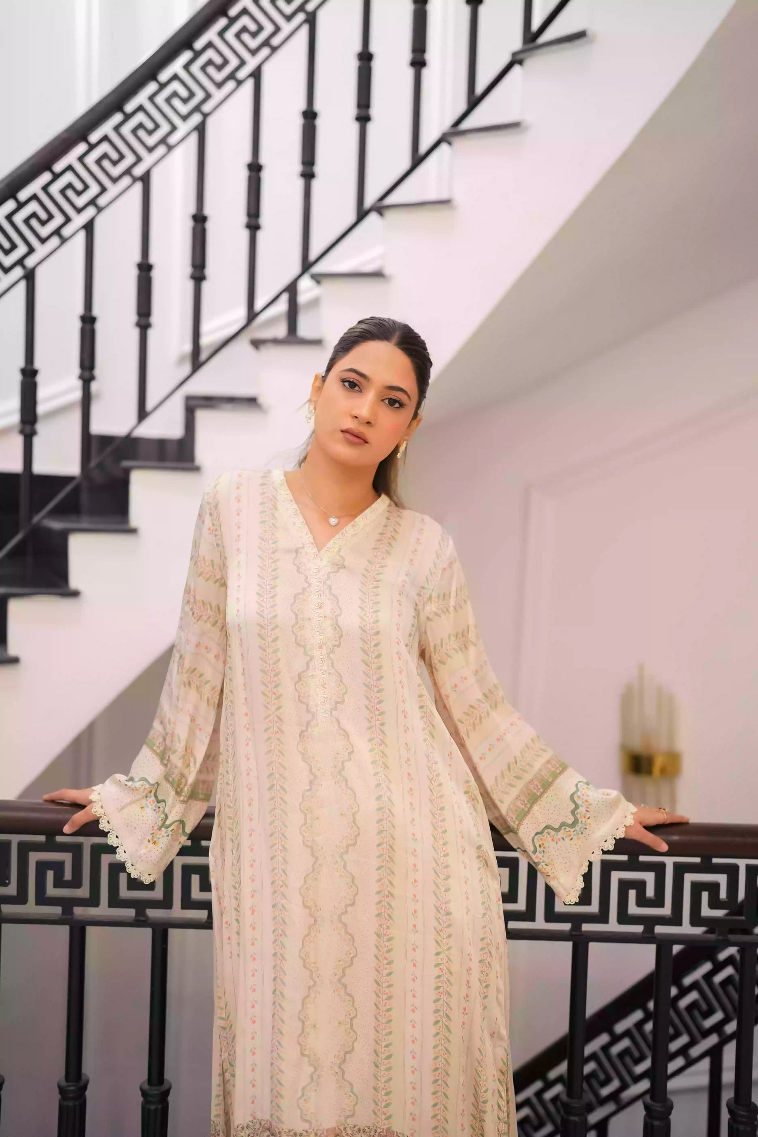 Elegant creamy ivory kameez adorned with delicate vertical floral trails, creating an elongated, graceful silhouette. Intricate lace inserts and subtle embellishments highlight the neckline, while wide, airy sleeves are finished with scalloped edges making this elegant piece ideal for daytime gatherings or refined evening events.