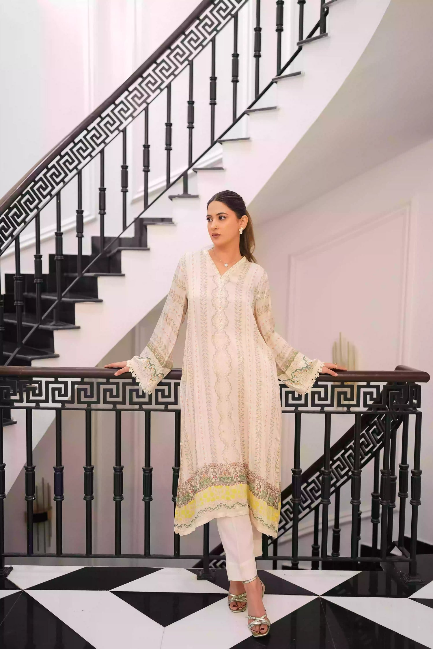 Elegant creamy ivory kameez adorned with delicate vertical floral trails, creating an elongated, graceful silhouette. Intricate lace inserts and subtle embellishments highlight the neckline, while wide, airy sleeves are finished with scalloped edges making this elegant piece ideal for daytime gatherings or refined evening events.