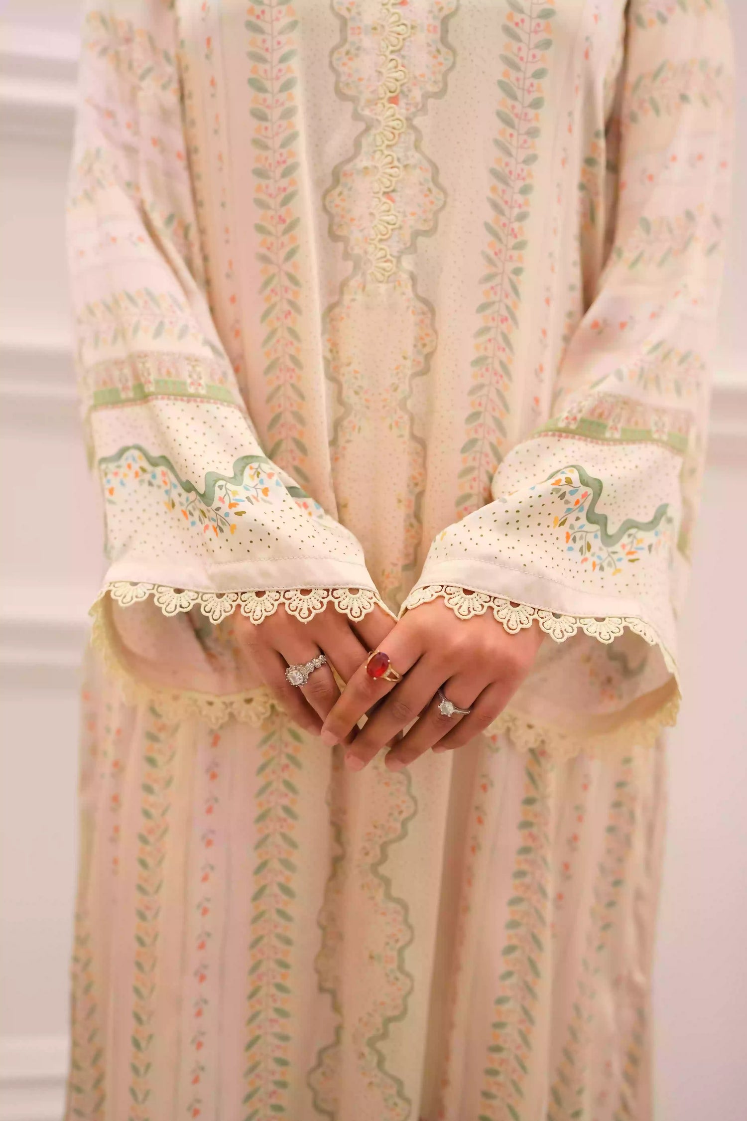 Elegant creamy ivory kameez adorned with delicate vertical floral trails, creating an elongated, graceful silhouette. Intricate lace inserts and subtle embellishments highlight the neckline, while wide, airy sleeves are finished with scalloped edges making this elegant piece ideal for daytime gatherings or refined evening events.