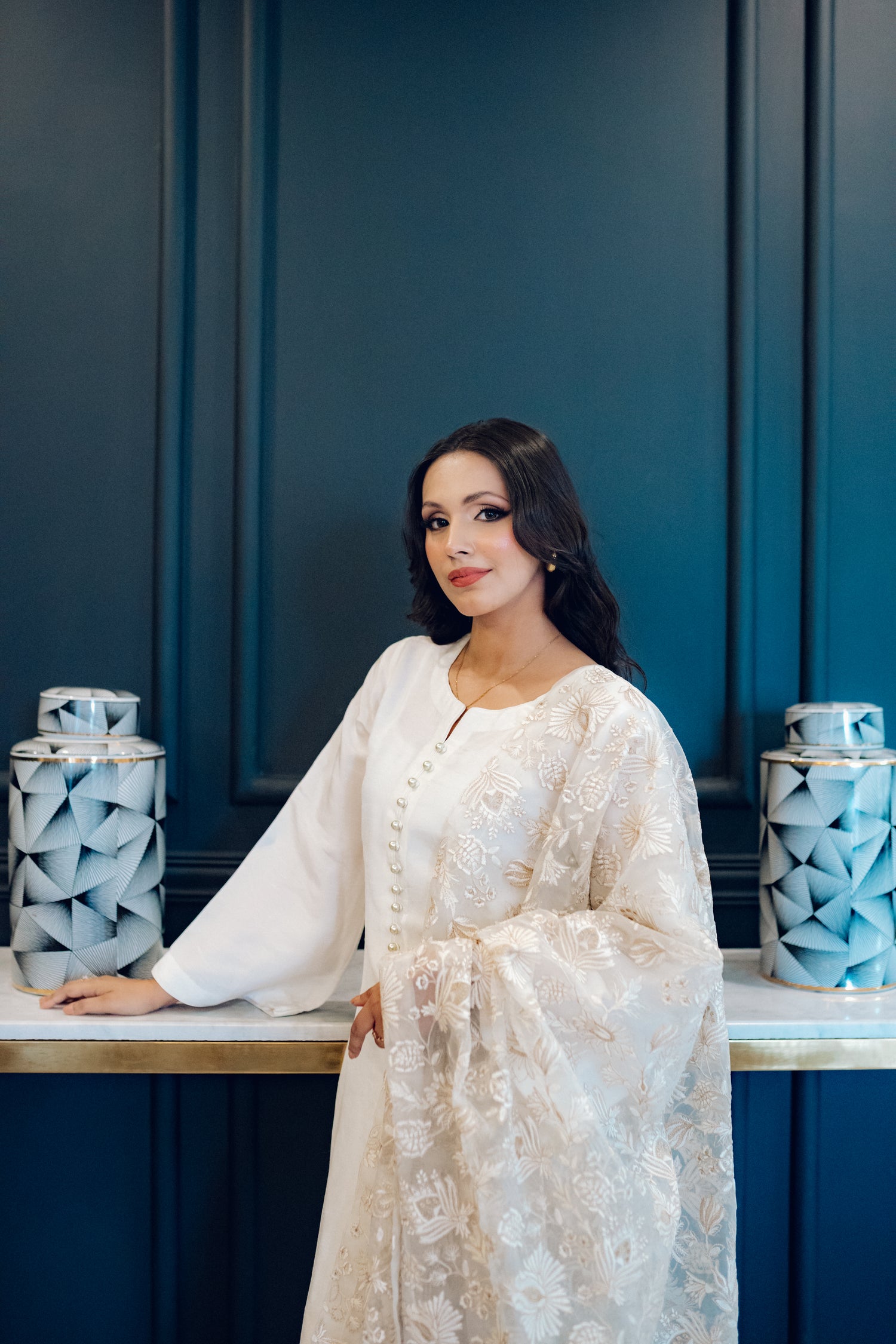 Ivory dress featuring delicate pearl buttons, paired with a shimmering tila and intricate threadwork dupatta, showcasing timeless elegance and artisanal craftsmanship.