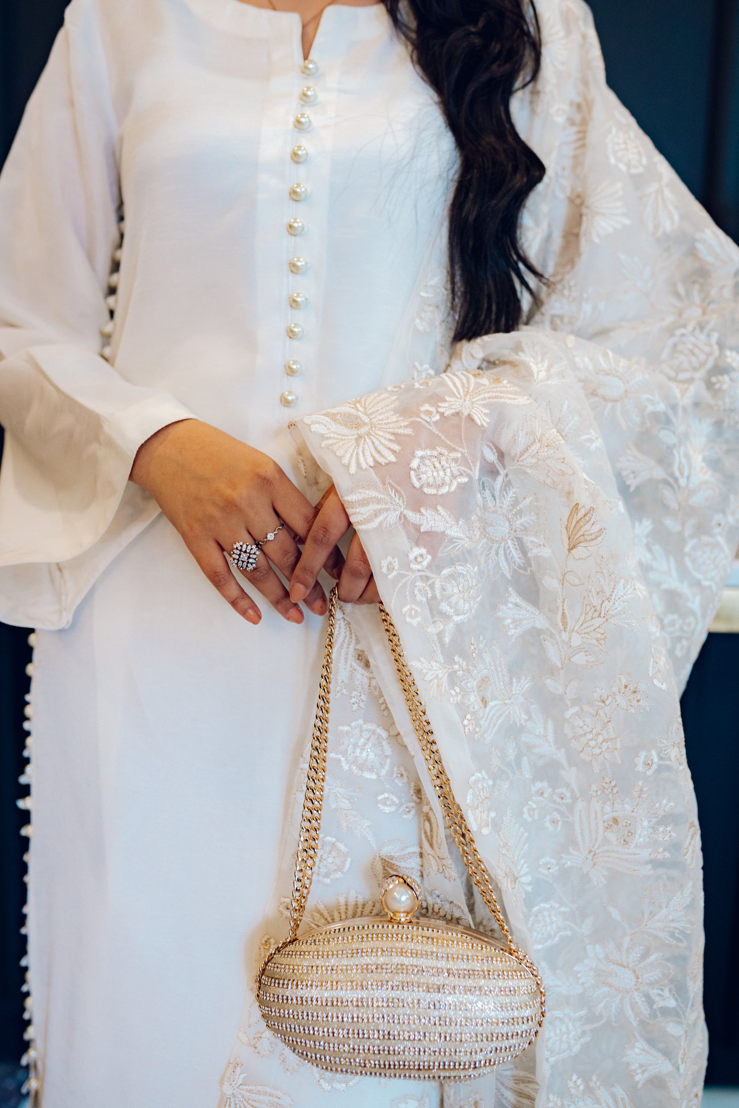Ivory dress featuring delicate pearl buttons, paired with a shimmering tila and intricate threadwork dupatta, showcasing timeless elegance and artisanal craftsmanship.
