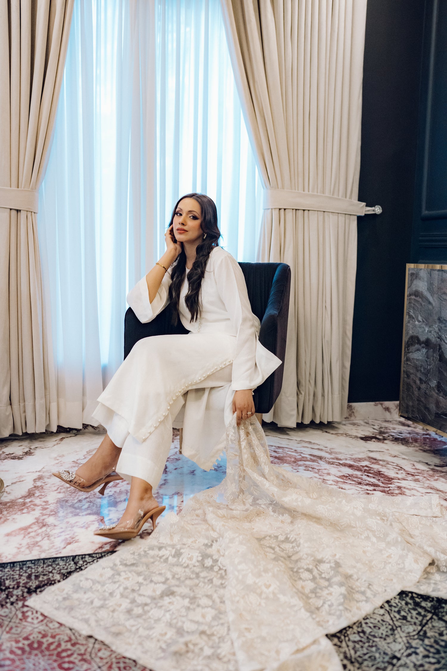 Ivory dress featuring delicate pearl buttons, paired with a shimmering tila and intricate threadwork dupatta, showcasing timeless elegance and artisanal craftsmanship.